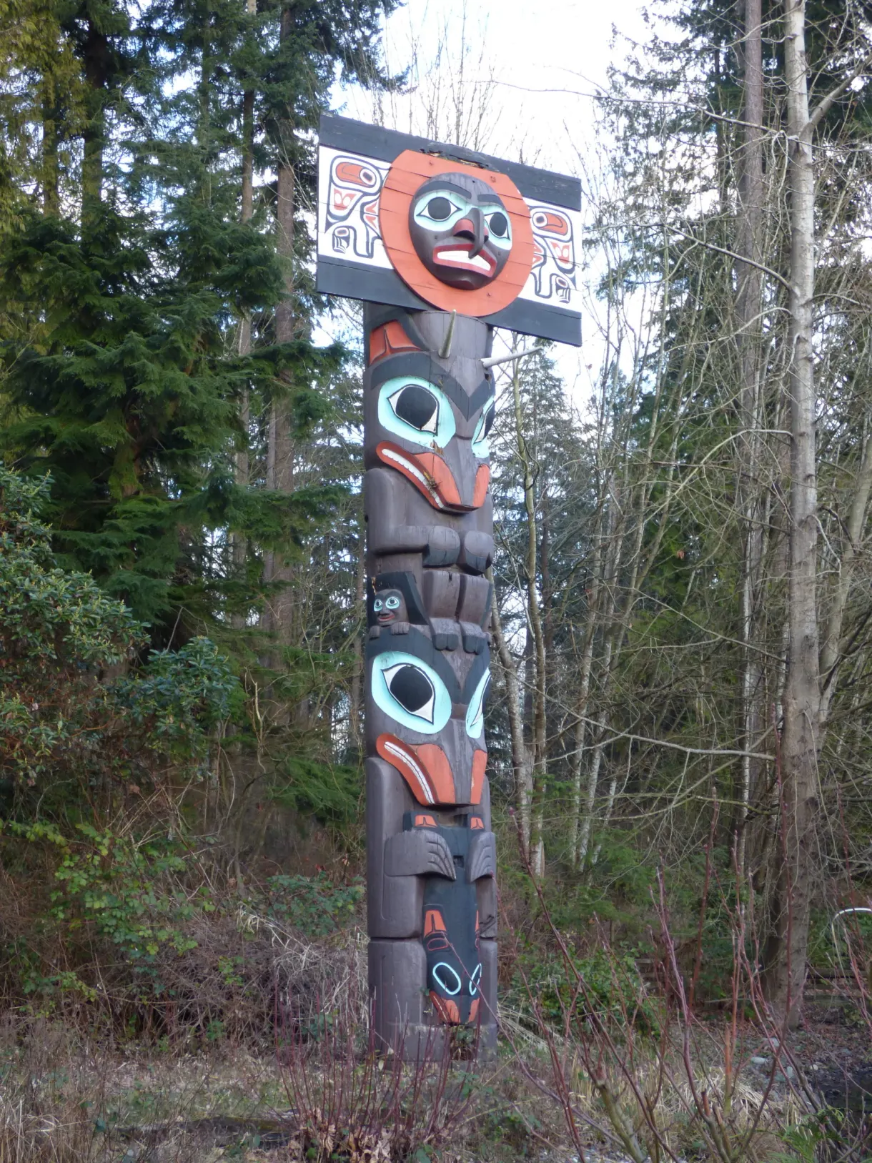 Colourful totem pole with stacked faces seen close up
