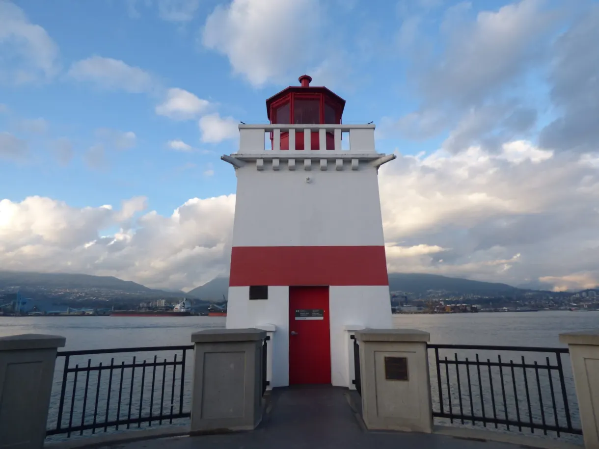 White lighthouse with a red band at the end of the point