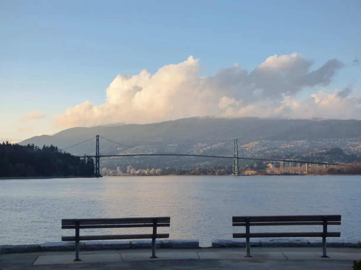 Two empty benches facing the strait and the bridge
