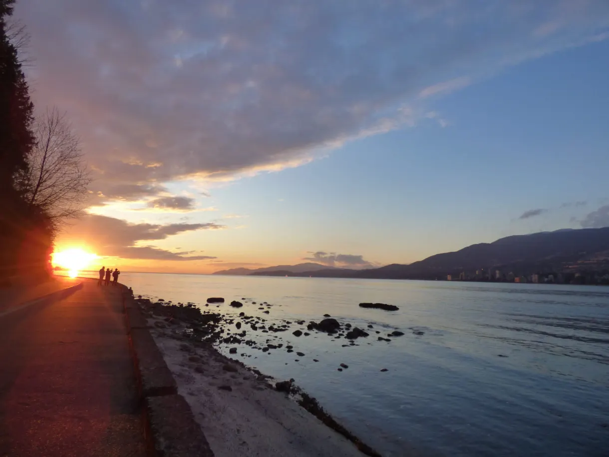 Strollers in silhouette in front of the low sun