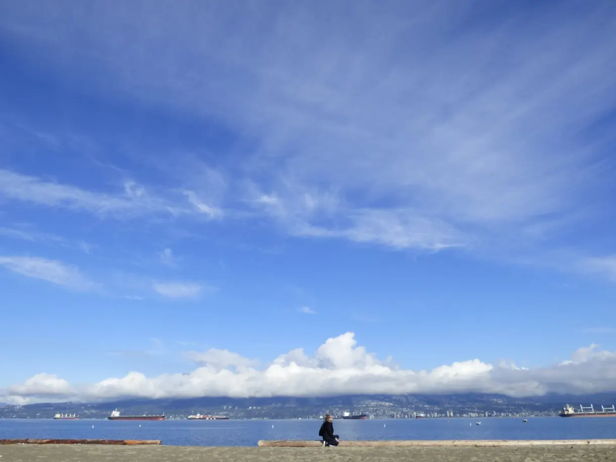 Lone seated silhouette under a vast beach sky