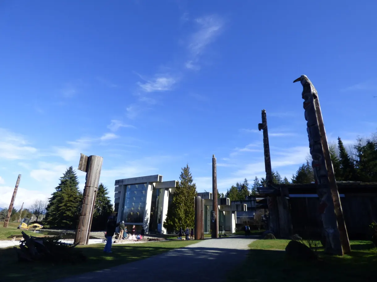 Totem poles and wooden frames in front of the campus museum