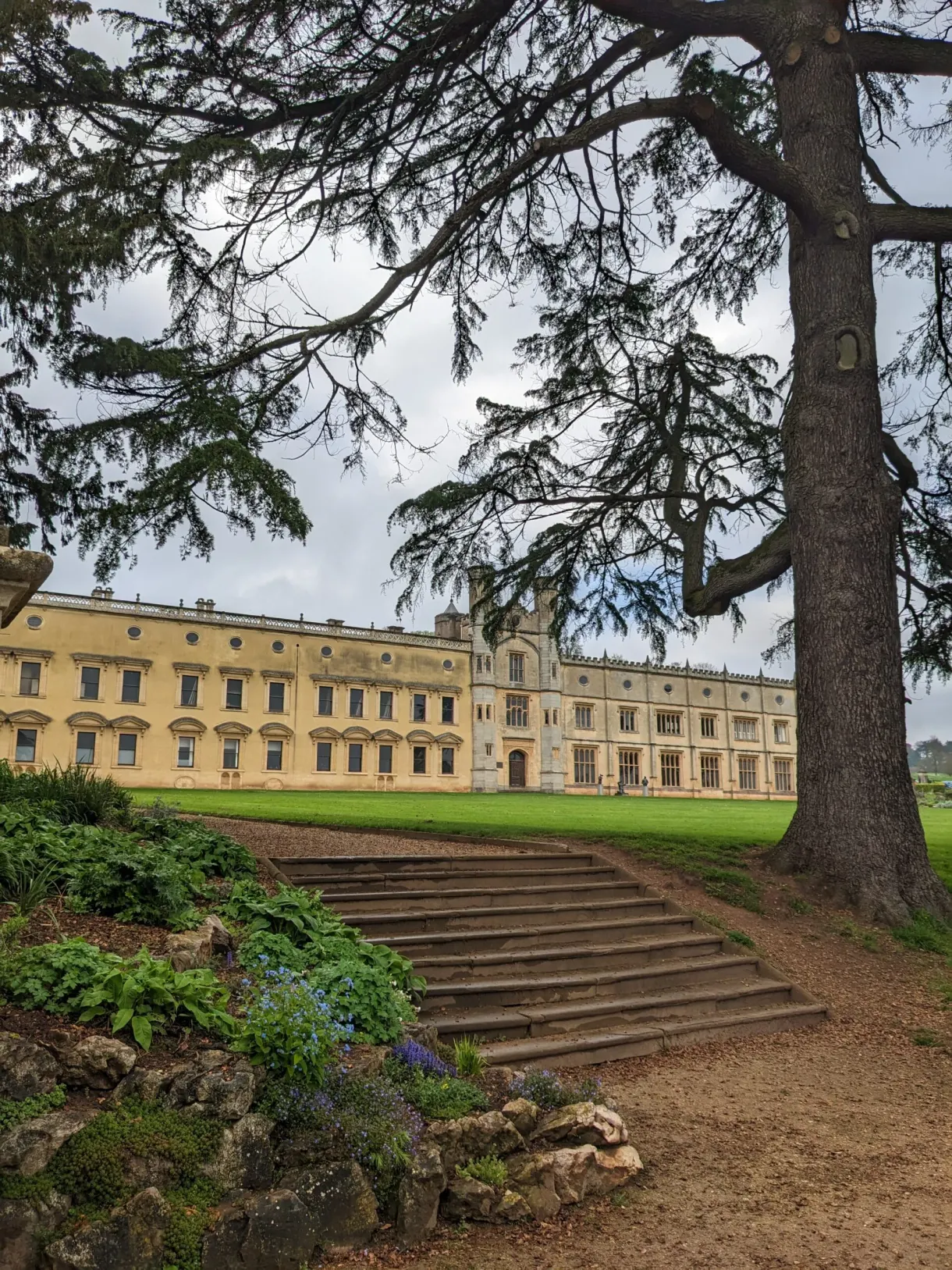 Georgian manor glimpsed from a staircase beneath the trees