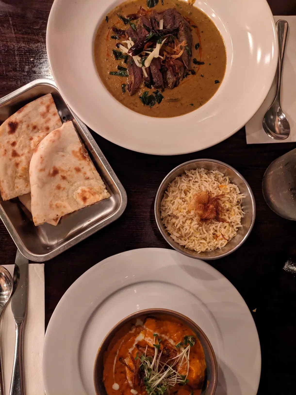 Curries, naan and rice set on a dark table