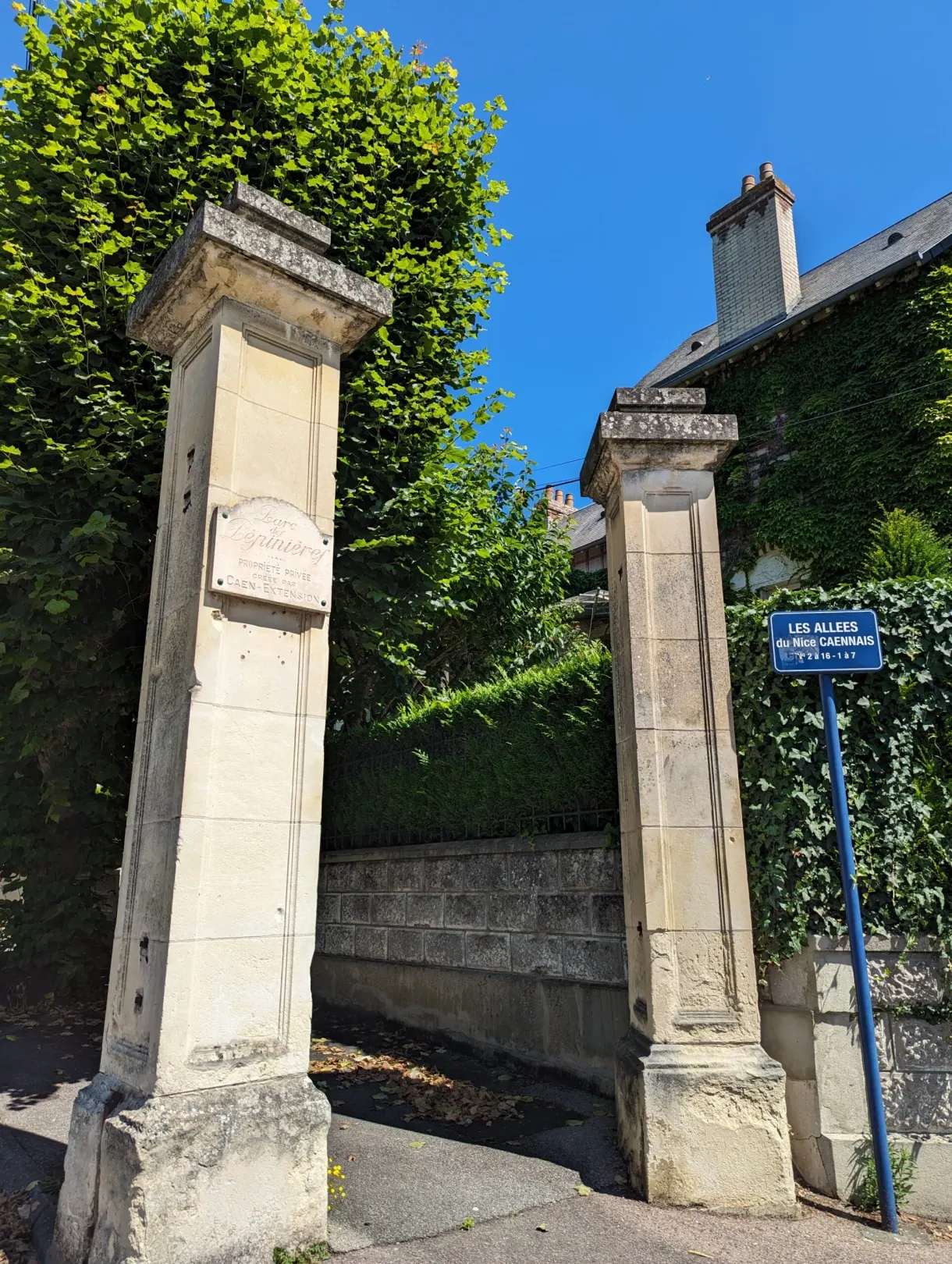 Two tall stone pillars marking the entrance to a shaded avenue