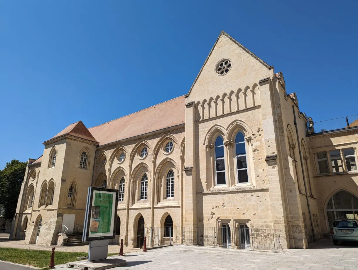 Pale stone facade pierced by a rose window and pointed windows