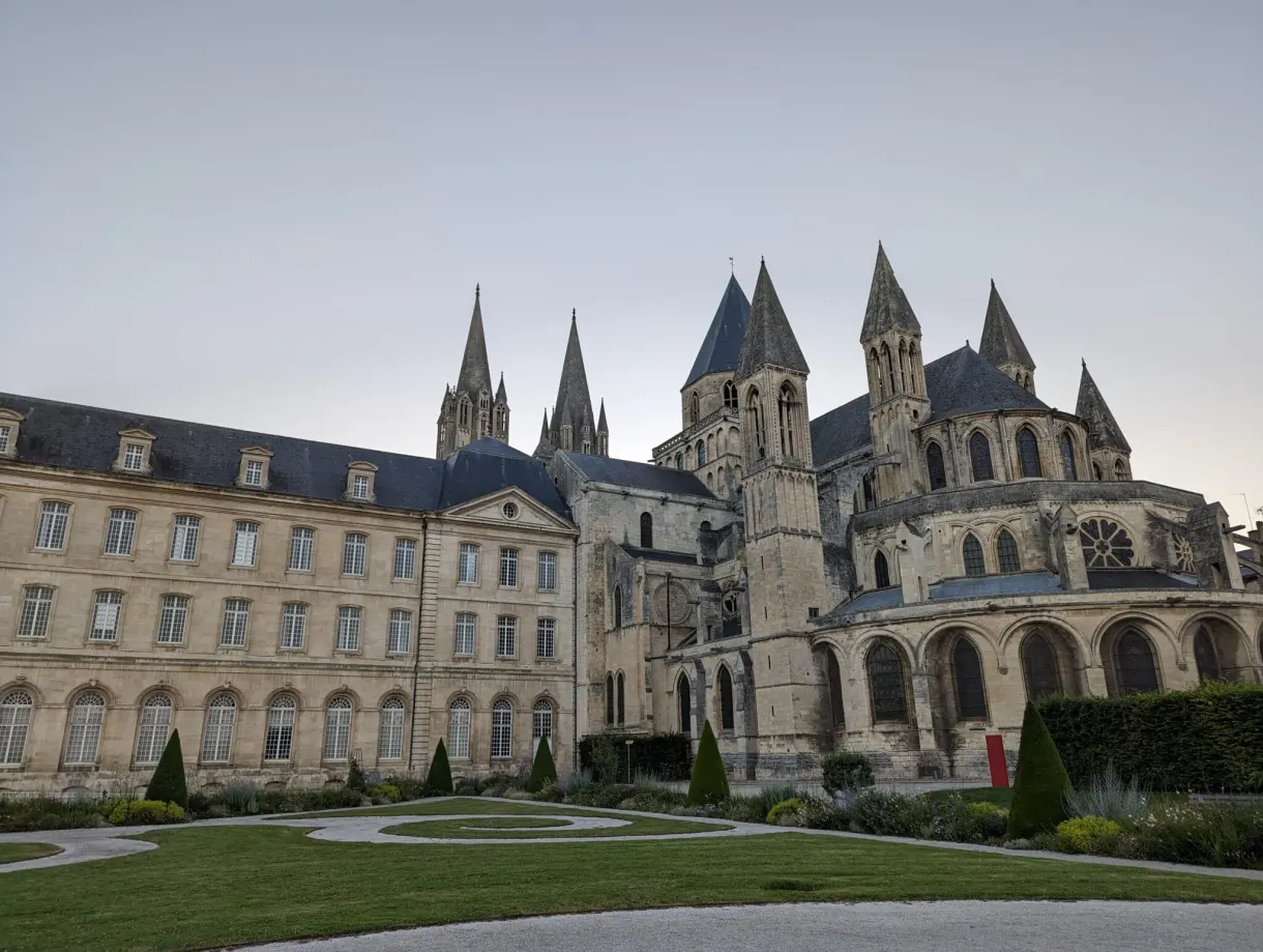 Long classical facade of the abbey in front of its patterned flower beds