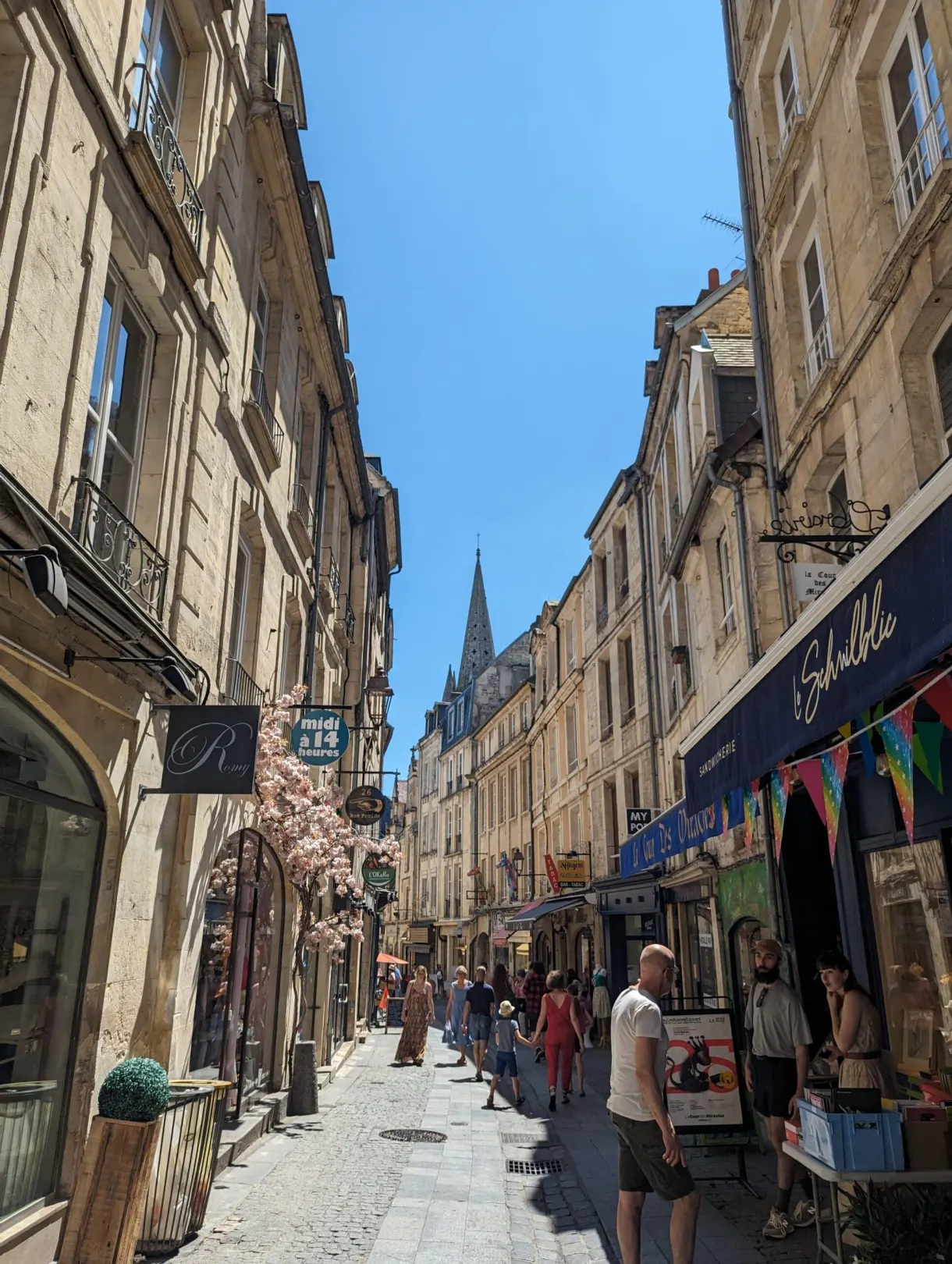 Busy pedestrian shopping street climbing towards a bell tower