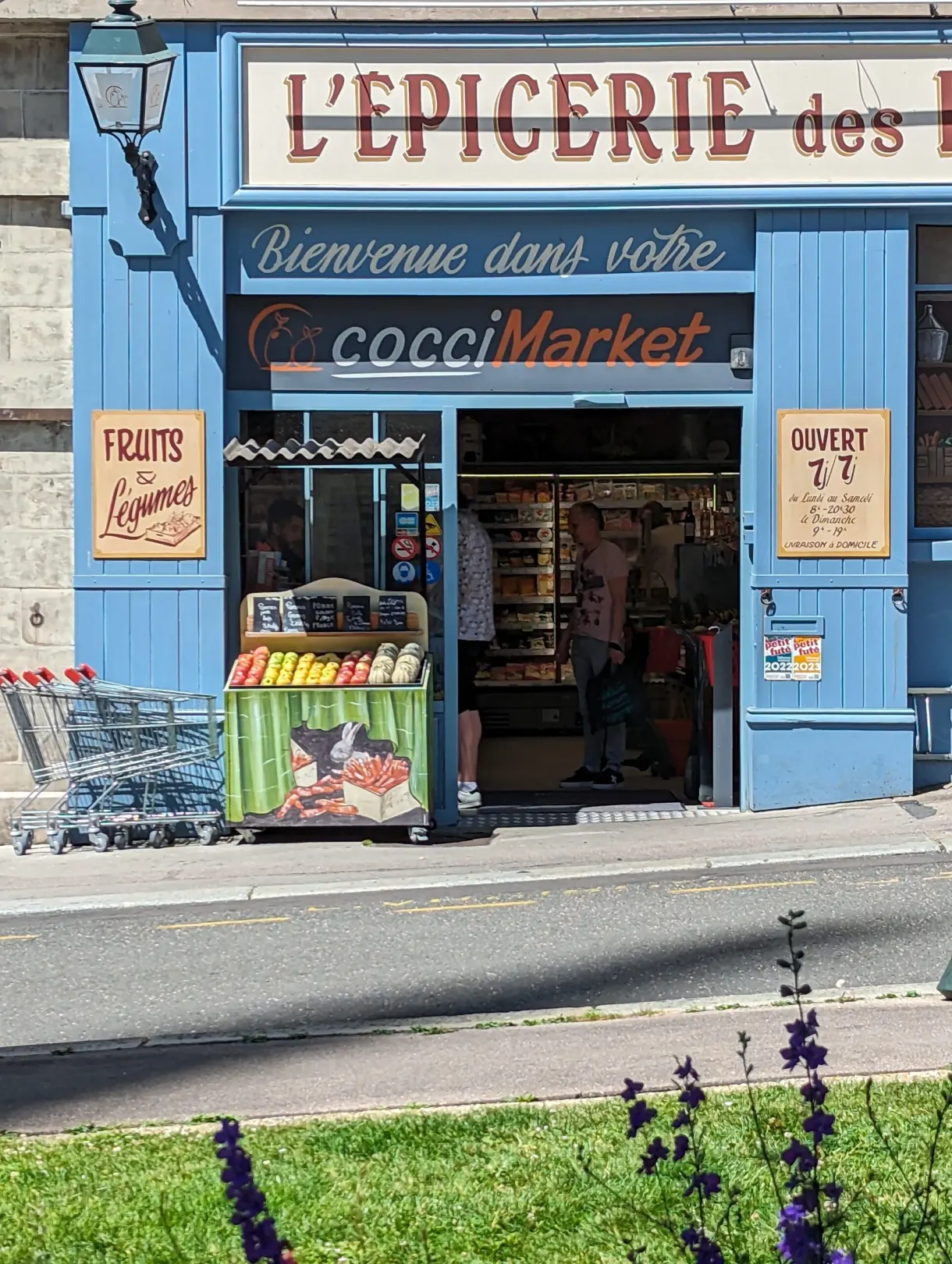 Blue shopfront of a neighbourhood grocery and its fruit stall