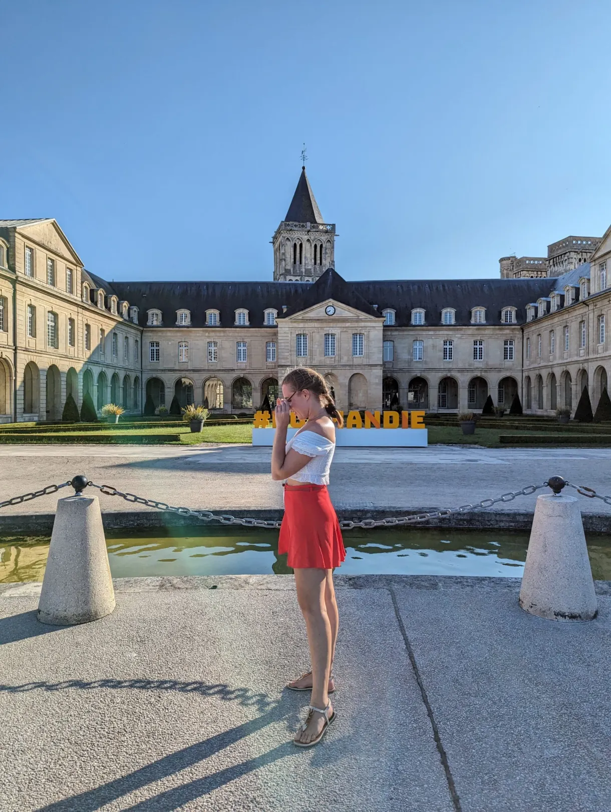 Yellow Normandie letters in the courtyard, visitor in a red skirt