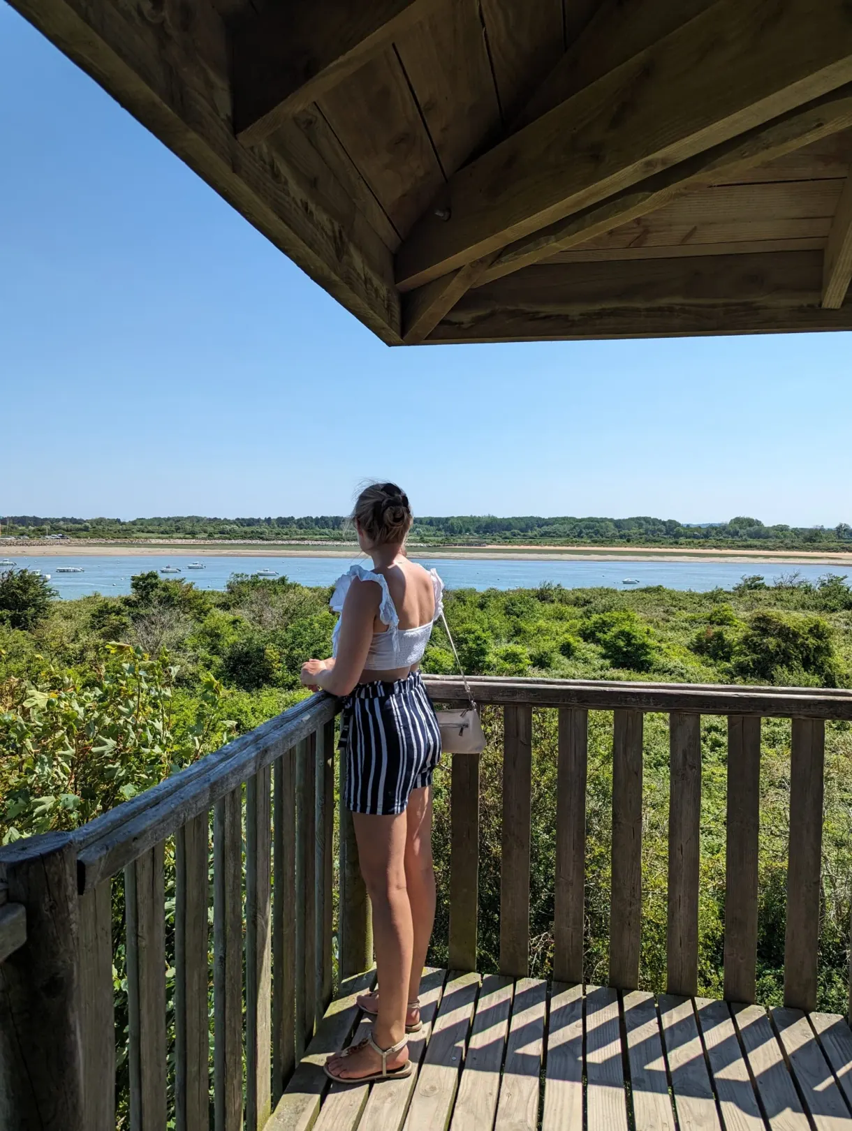 Woman leaning on a wooden observation hide facing the bay