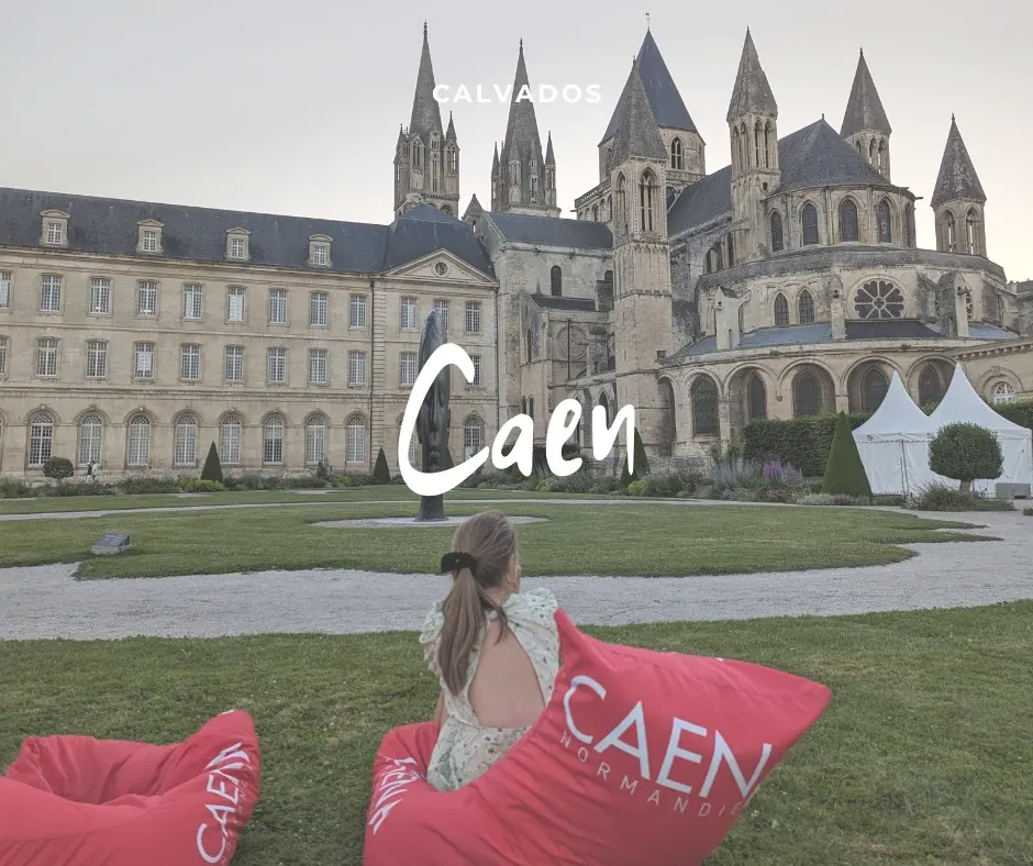 Visitor sitting on pink cushions facing the Abbaye aux Hommes