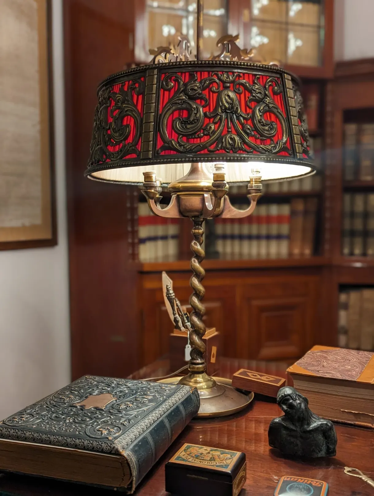 Art nouveau lamp with a red shade on a library desk
