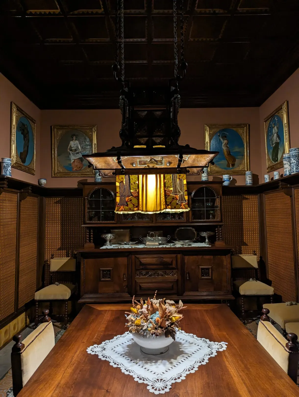 Wood-panelled dining room with a glass chandelier and pale pink walls