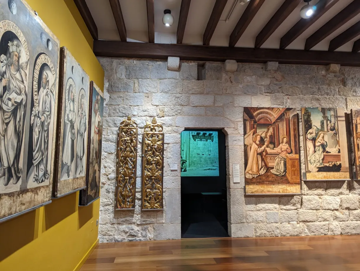 Painted altarpieces and bas-reliefs hung on a pale stone wall