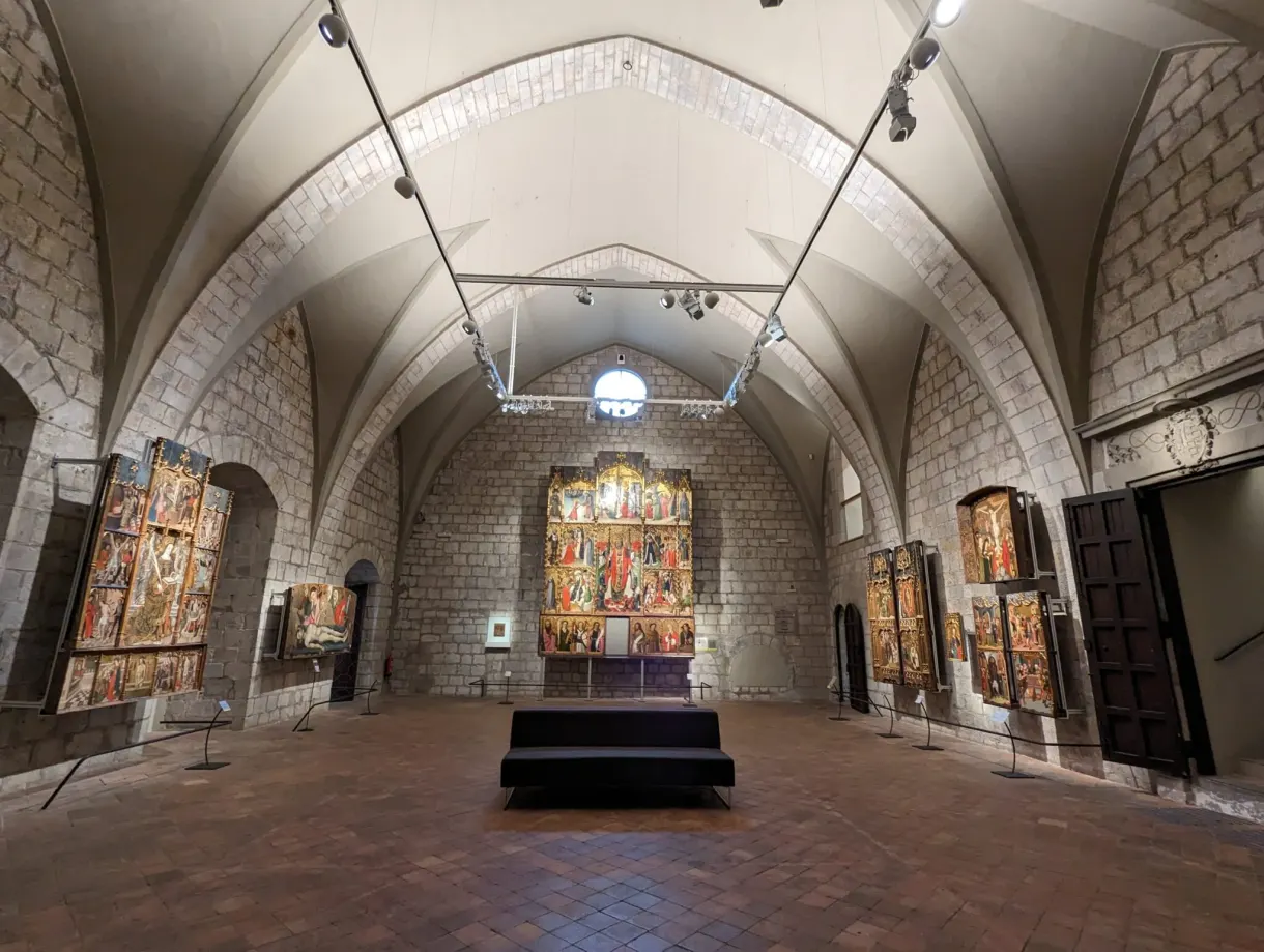 Vaulted room with altarpieces lined up along the stone walls