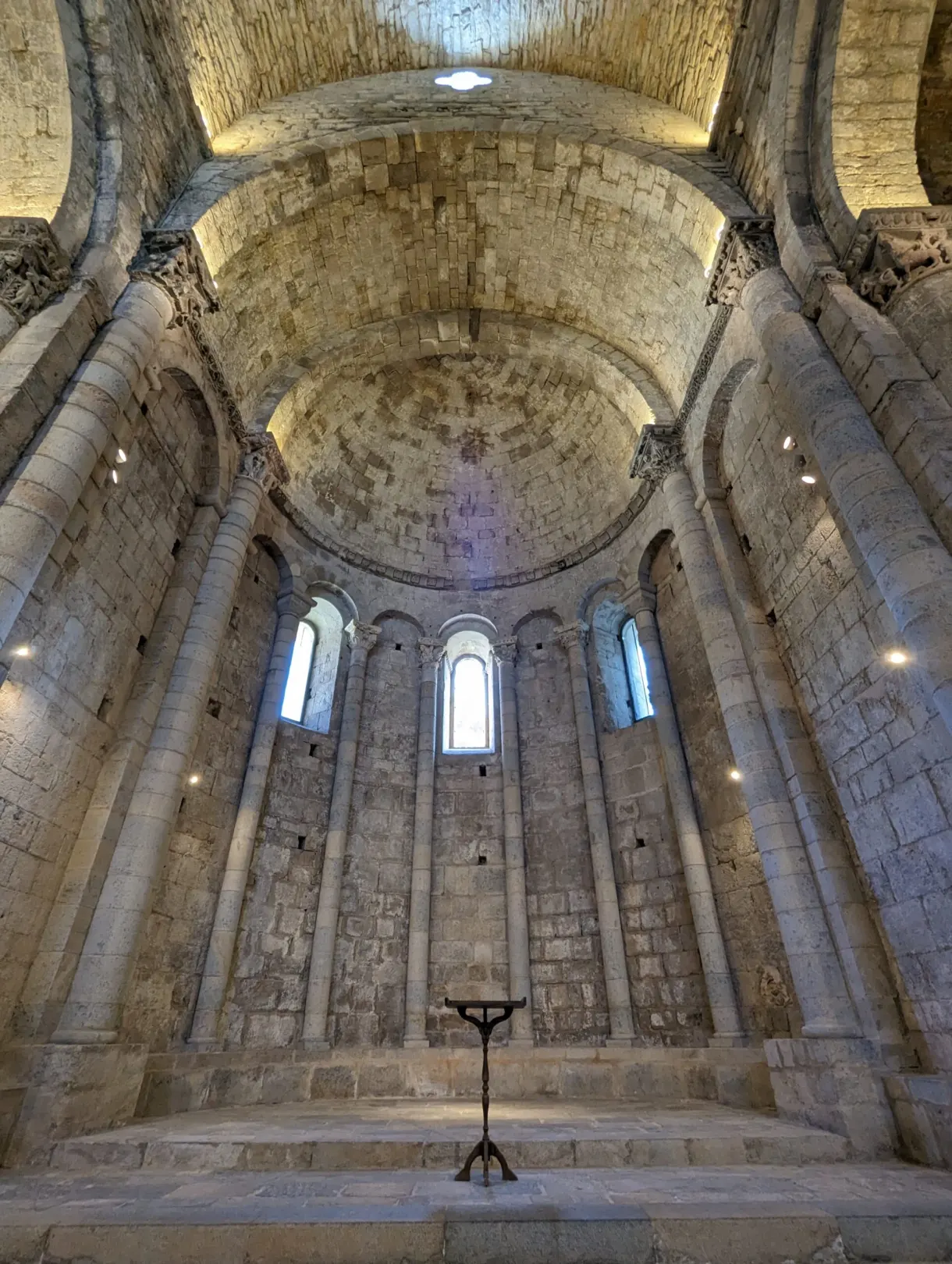 Romanesque apse in bare stone lit by three narrow windows