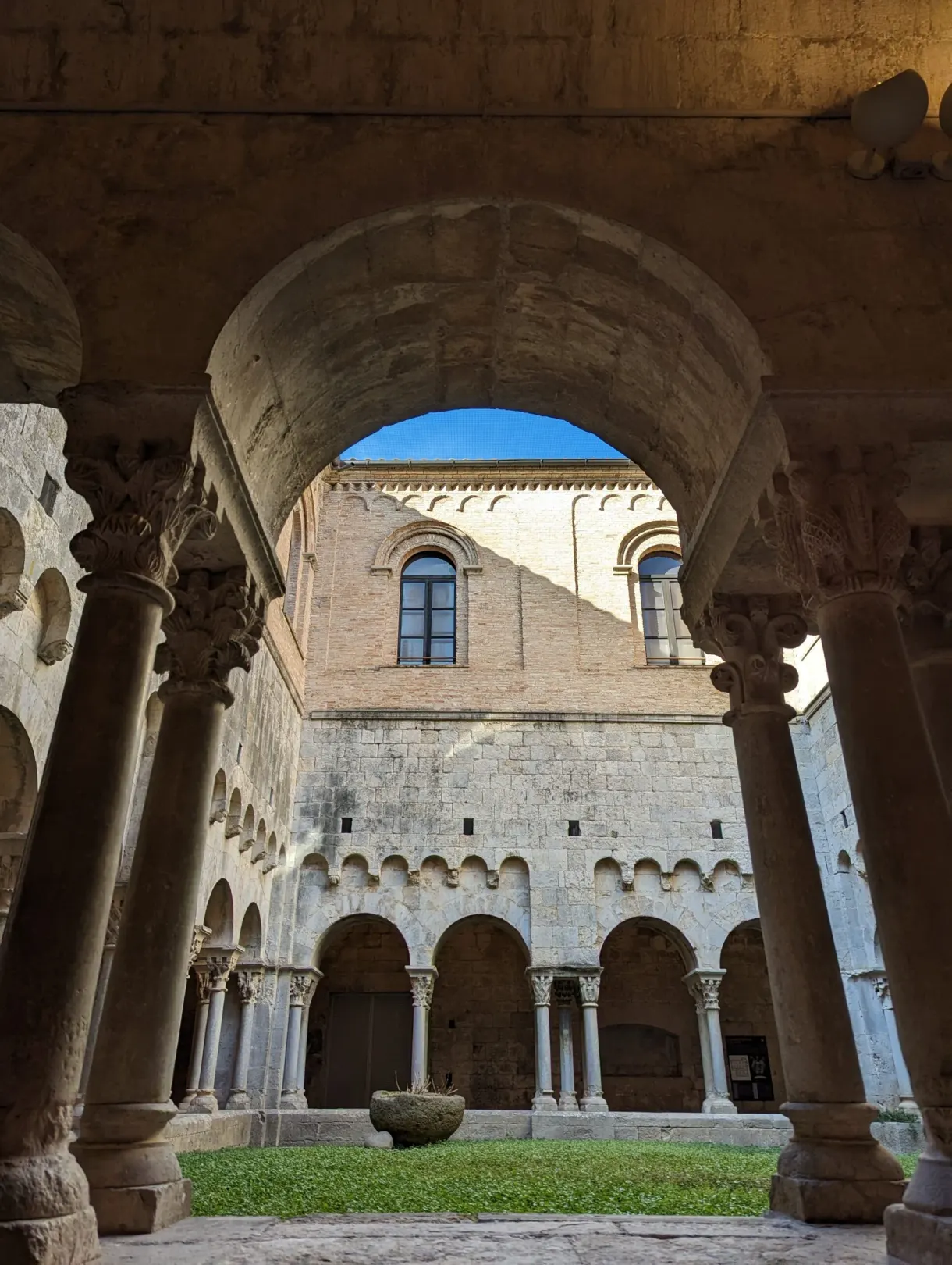 Romanesque cloister with carved capitals open to a blue sky