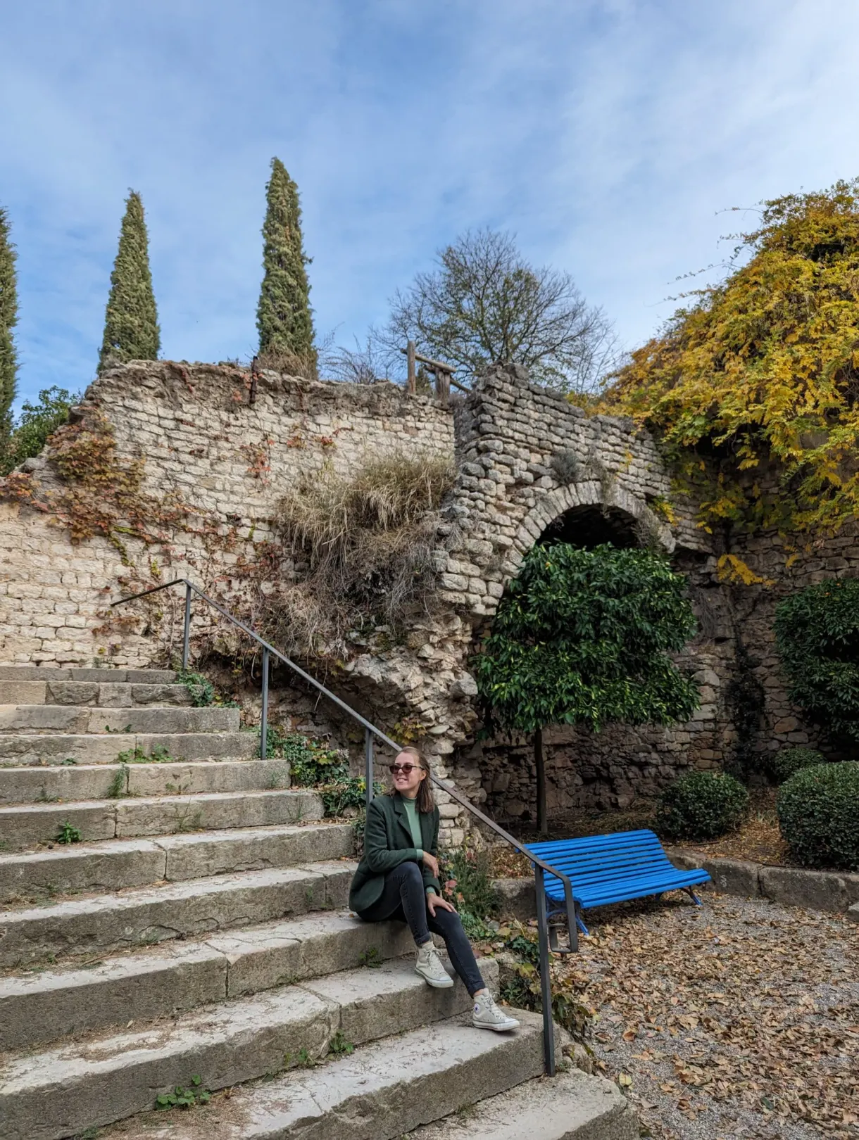 Woman sitting on a stone staircase near a blue bench