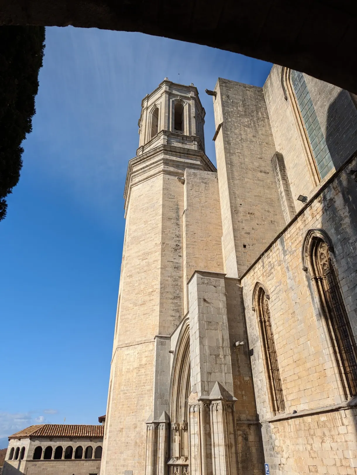 Square bell tower of the cathedral framed under a stone arch