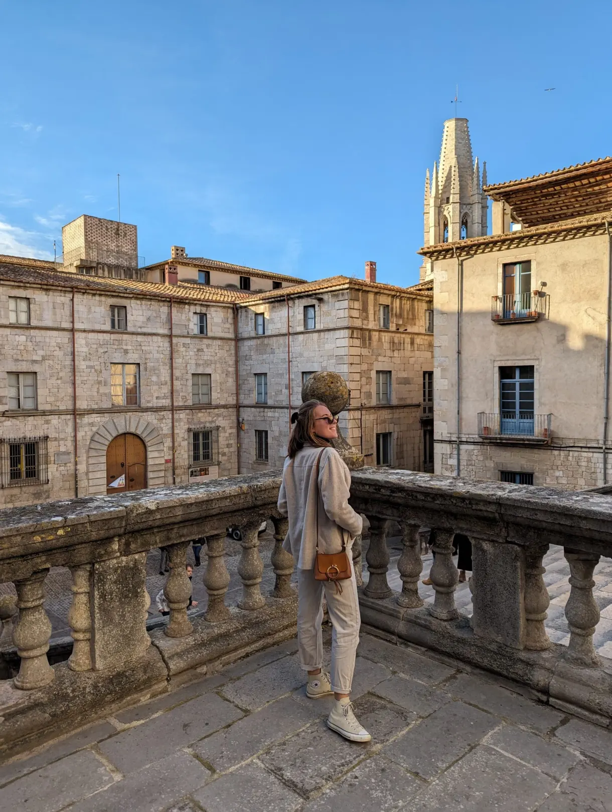 Woman leaning on a stone balustrade facing the golden facades
