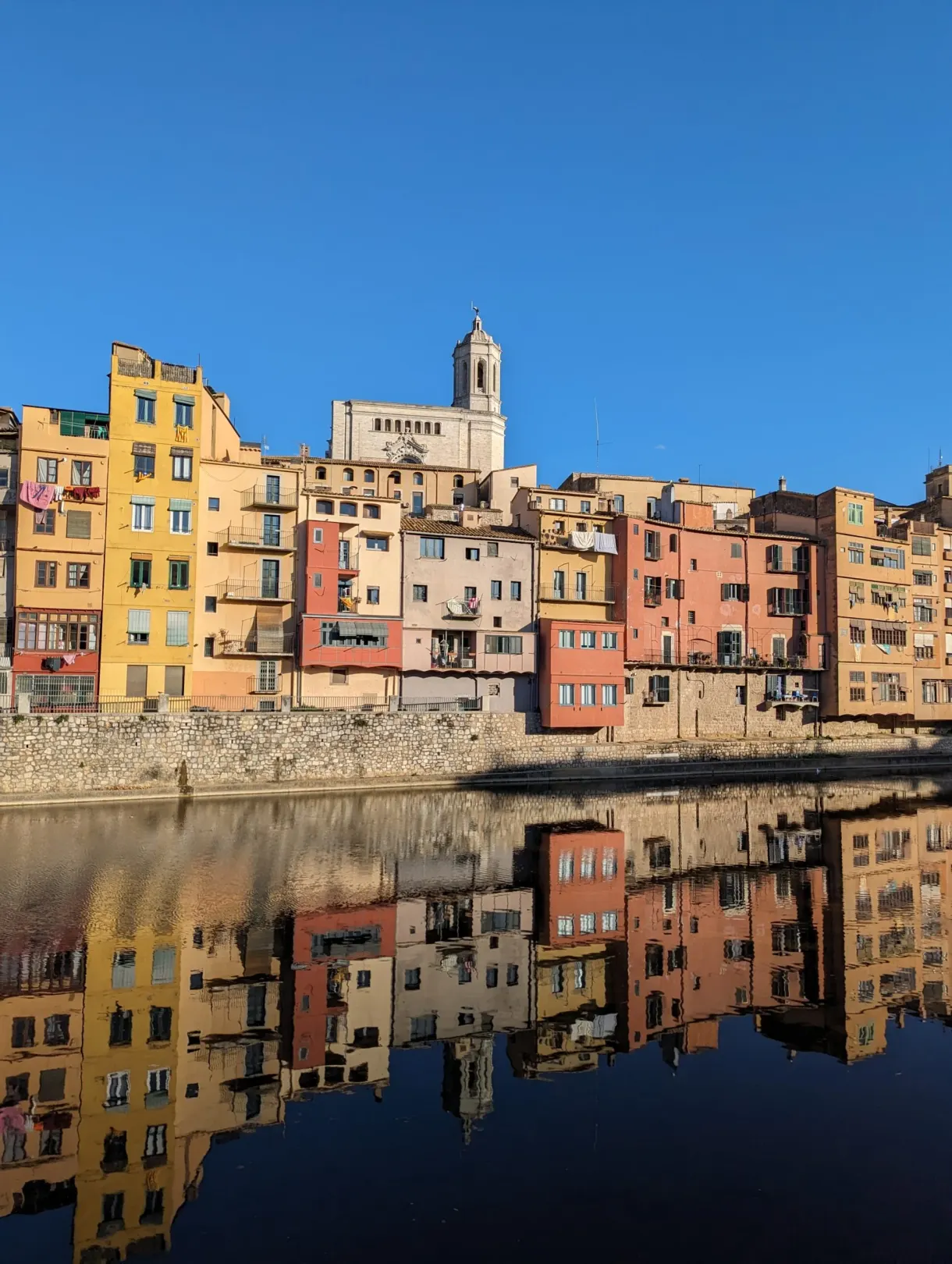 Yellow and pink facades of the Onyar reflected in the still water