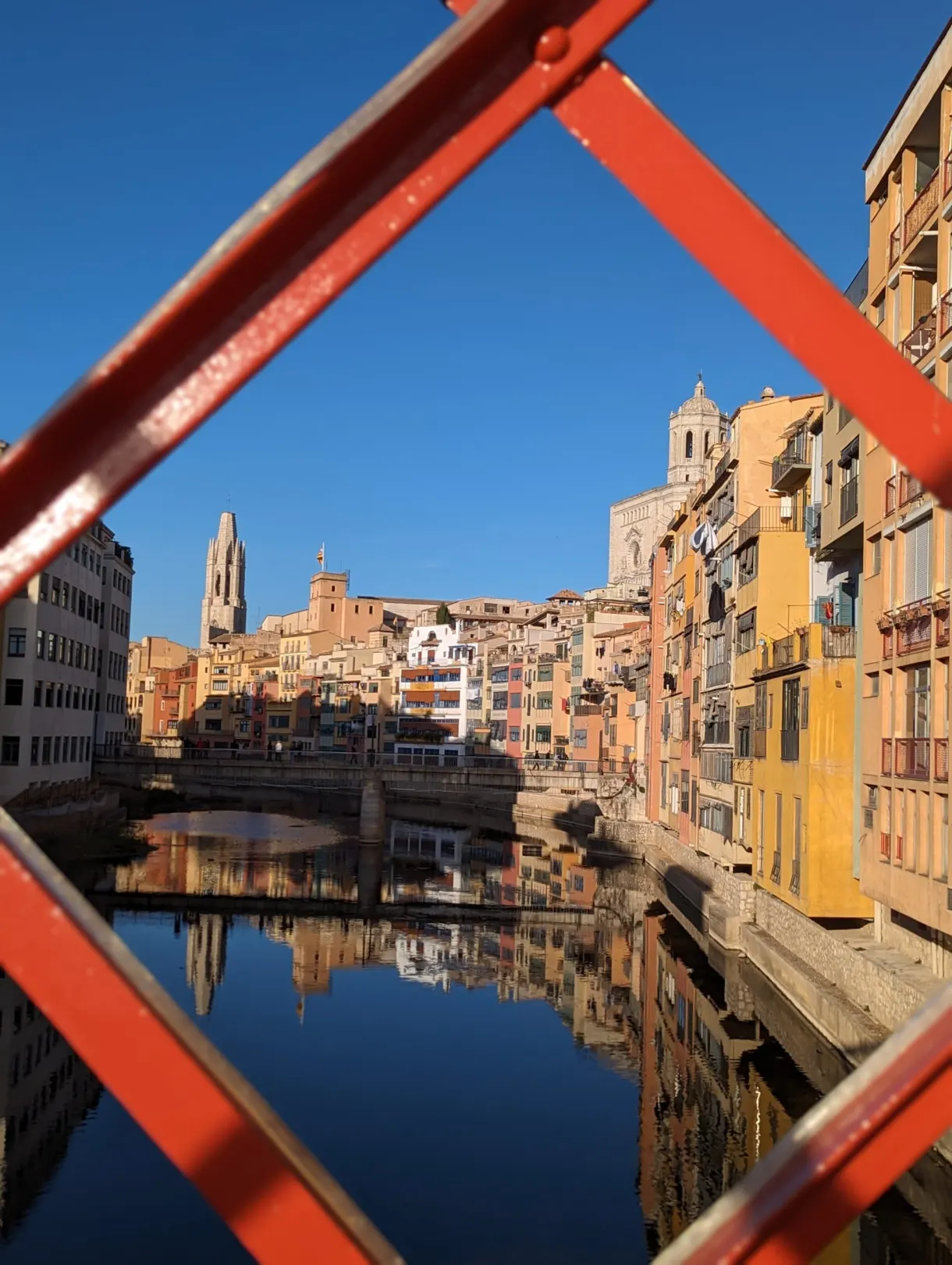 Houses of the Onyar framed between the red girders of a footbridge