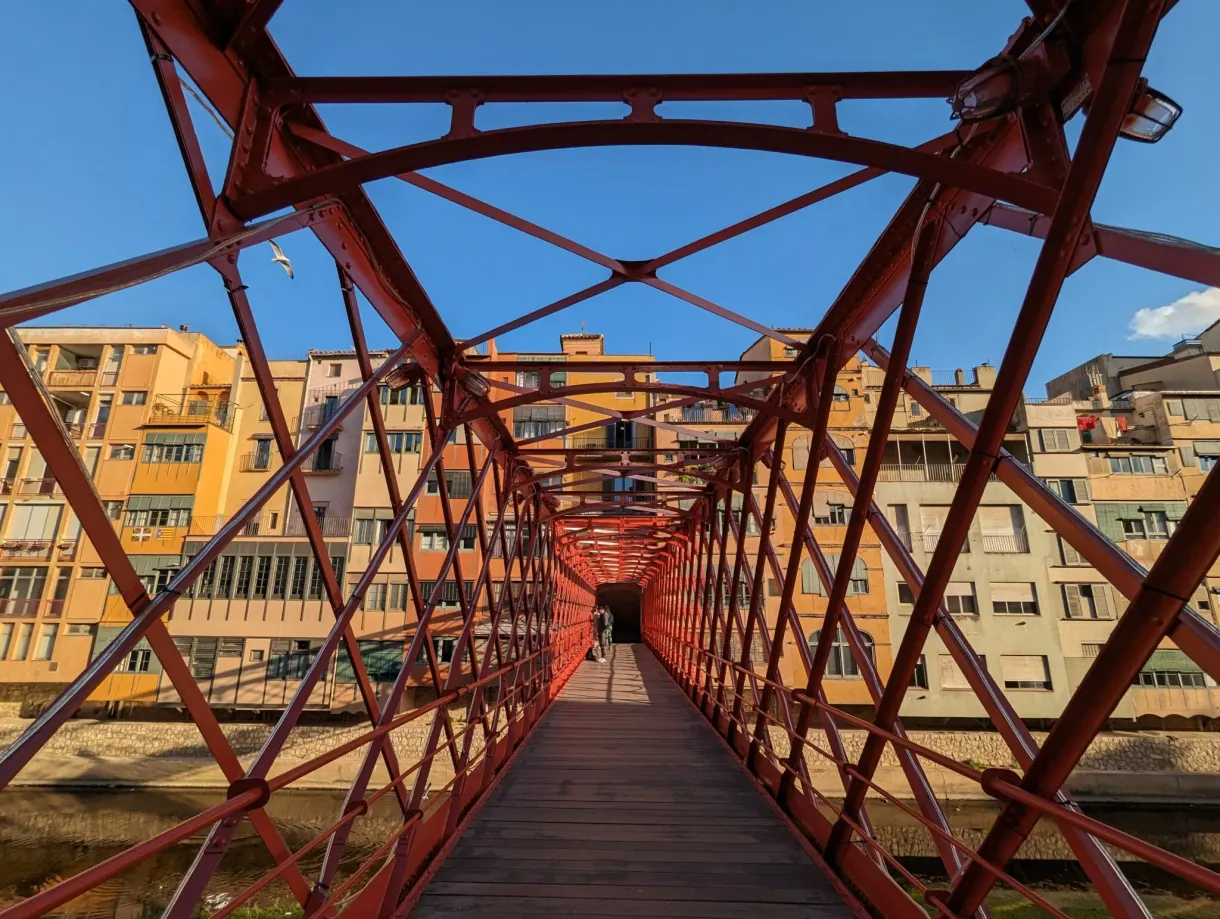 Red structure of a metal footbridge crossed by a walker