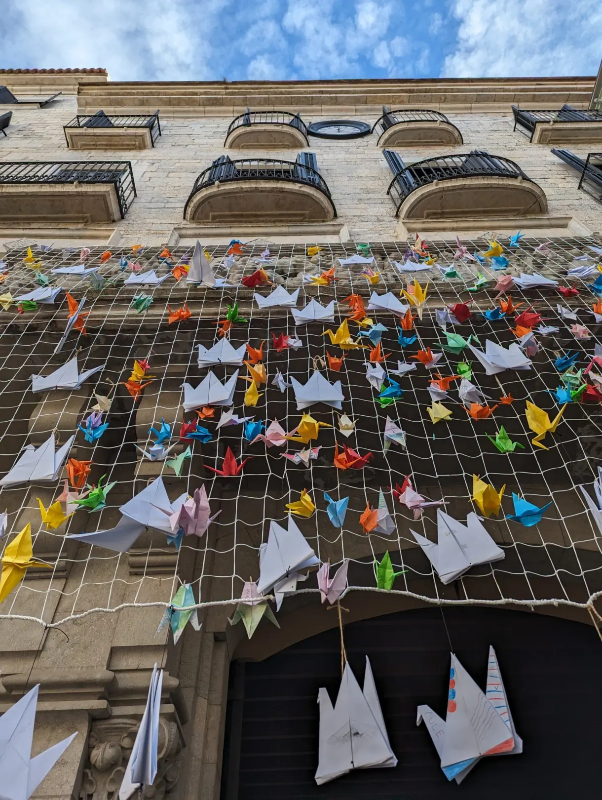 Net of colourful origami stretched in front of a facade in the old centre