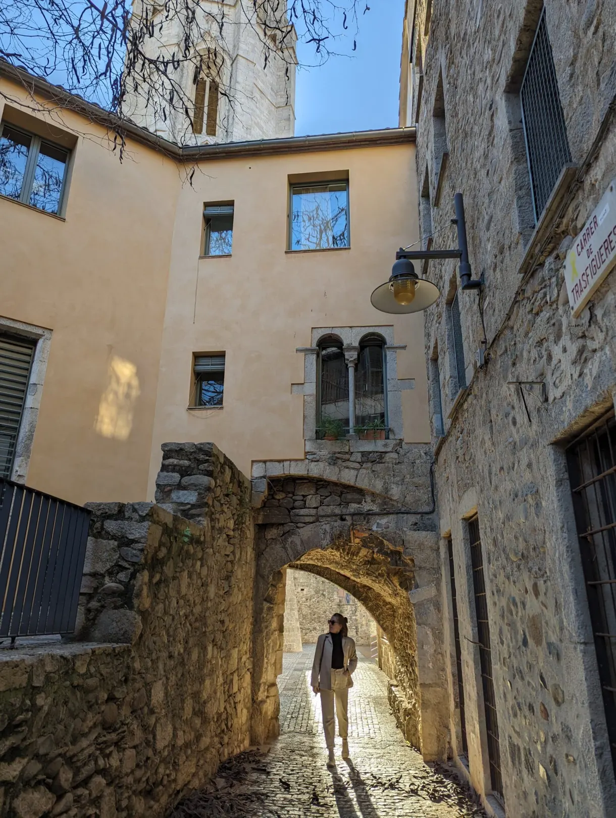 Passer-by under a stone arch in a cobbled lane