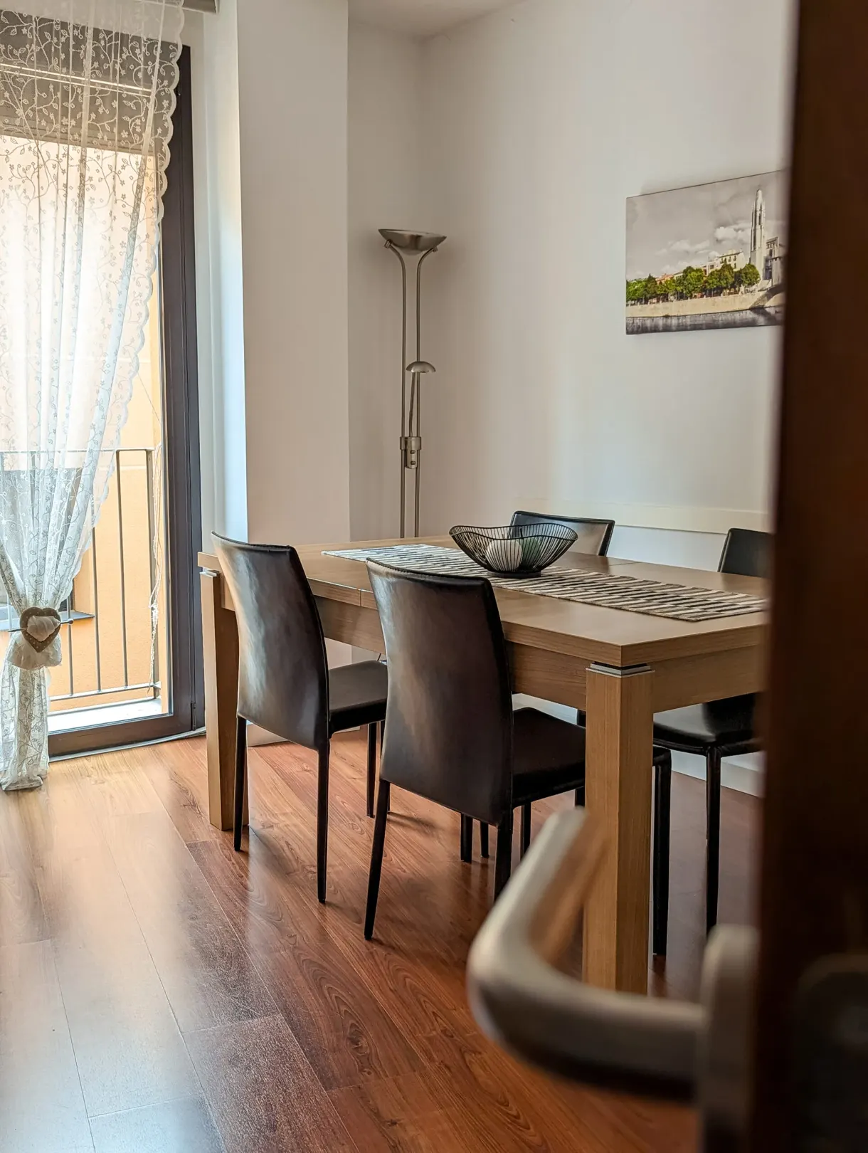 Pale wood dining table in front of a net-curtained window