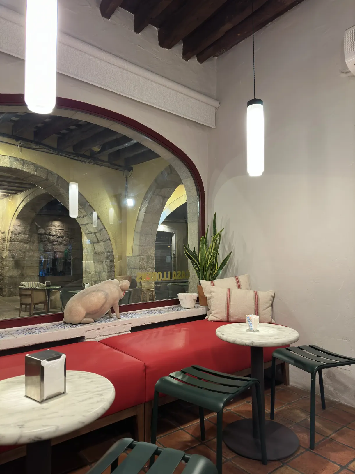 Cafe room with red banquettes and a pig sculpture in the window