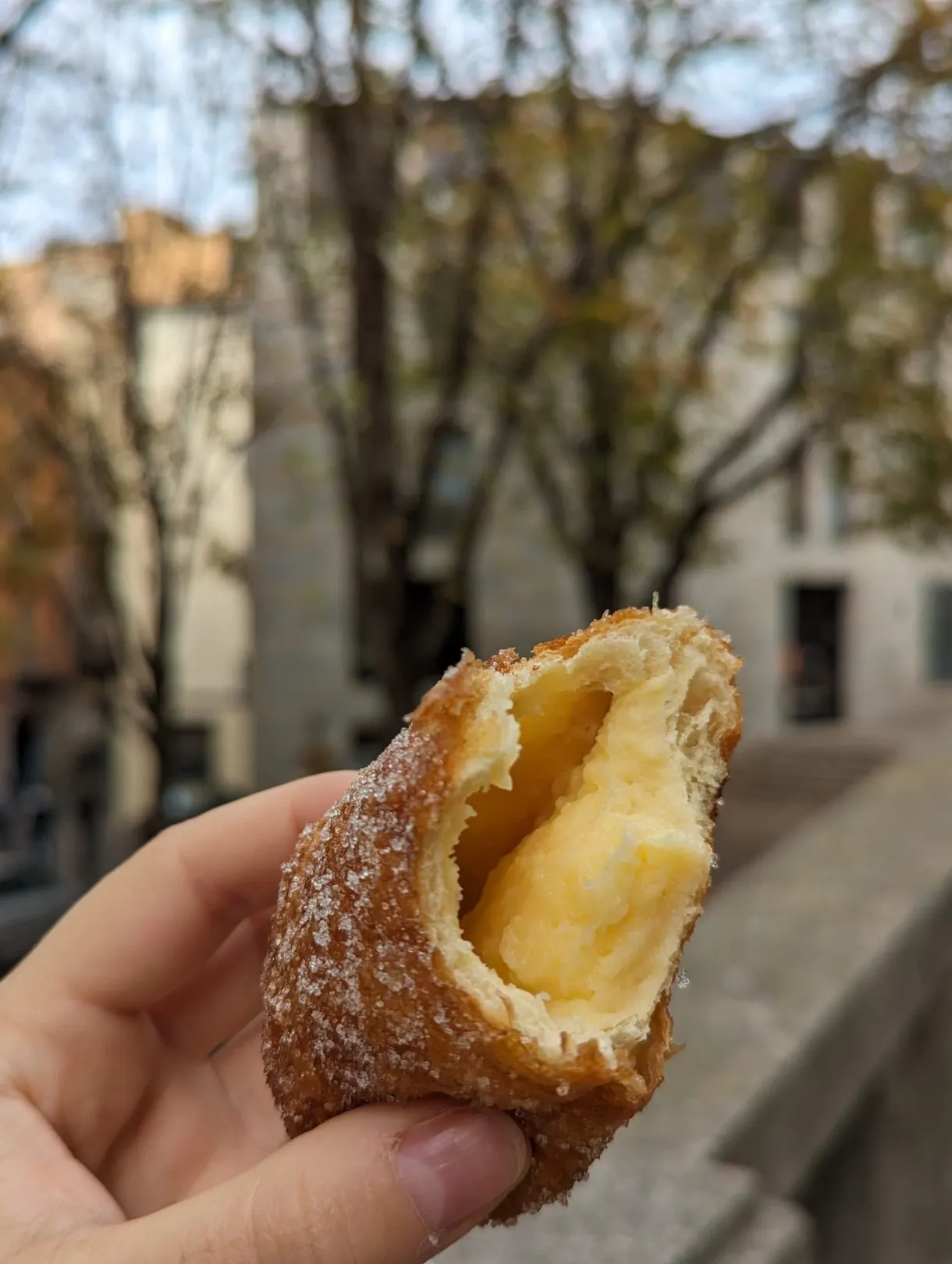 Cream-filled doughnut held in the hand in the street