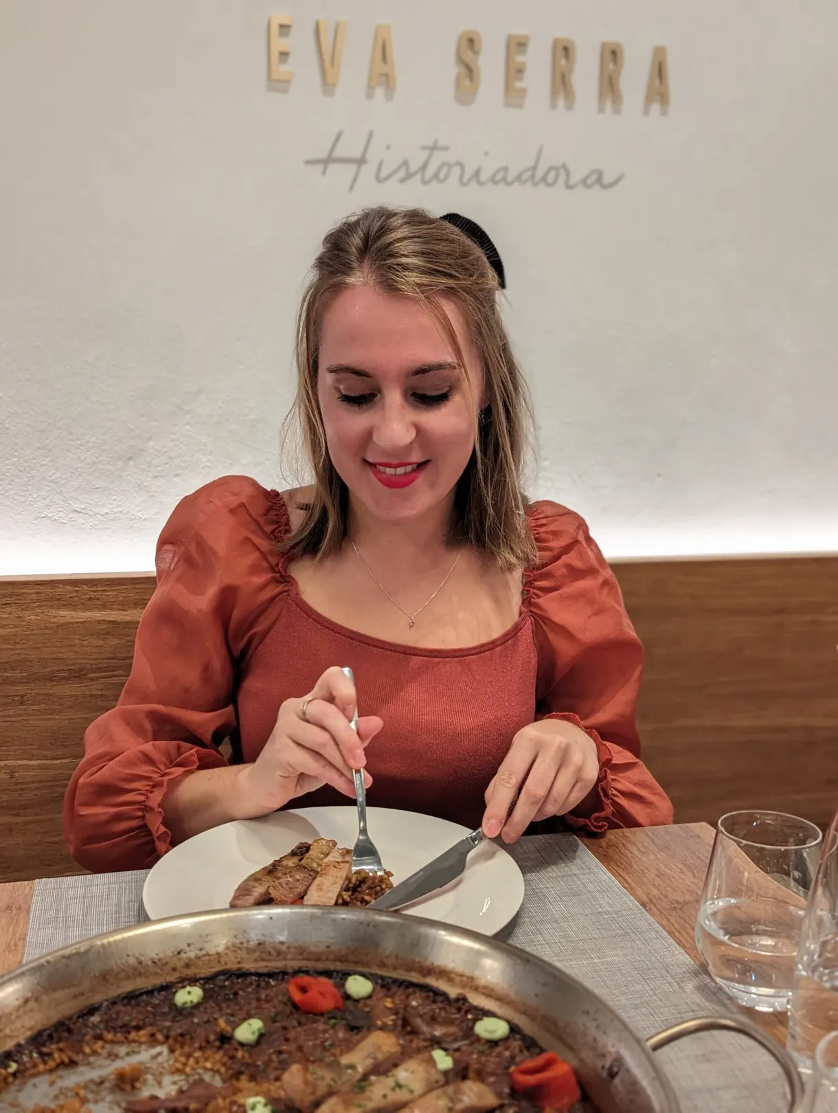 Woman at a table in front of a paella served in a restaurant