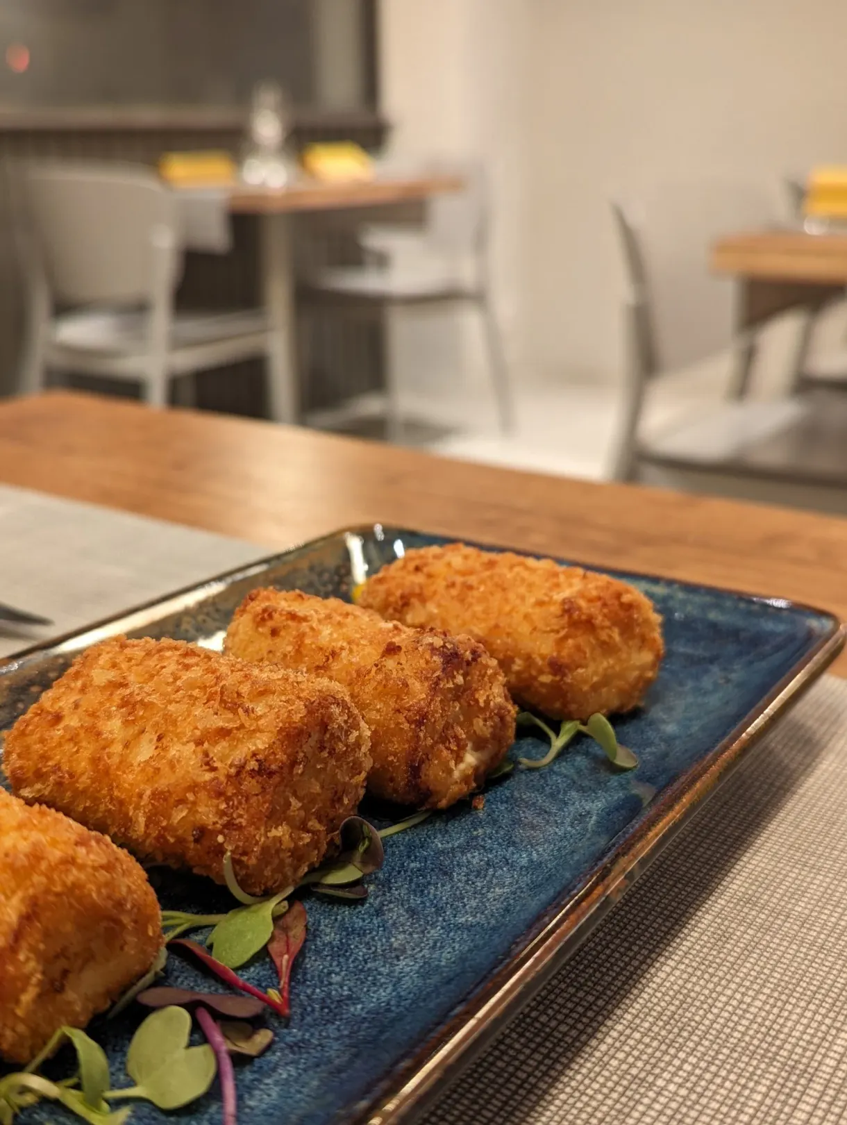 Golden croquettes lined up on a blue plate