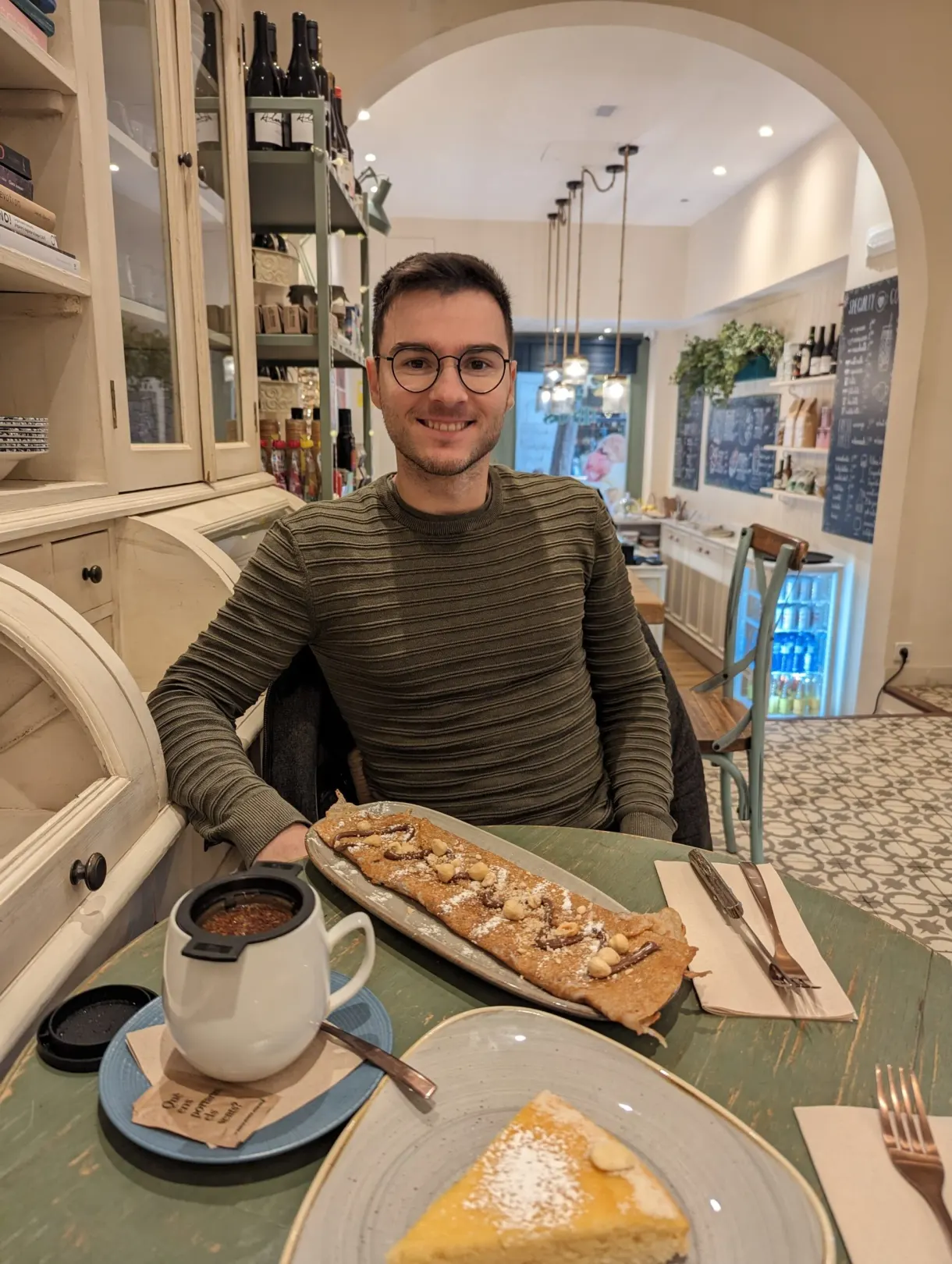 Man at a table with a slice of tart and a sweet pastry