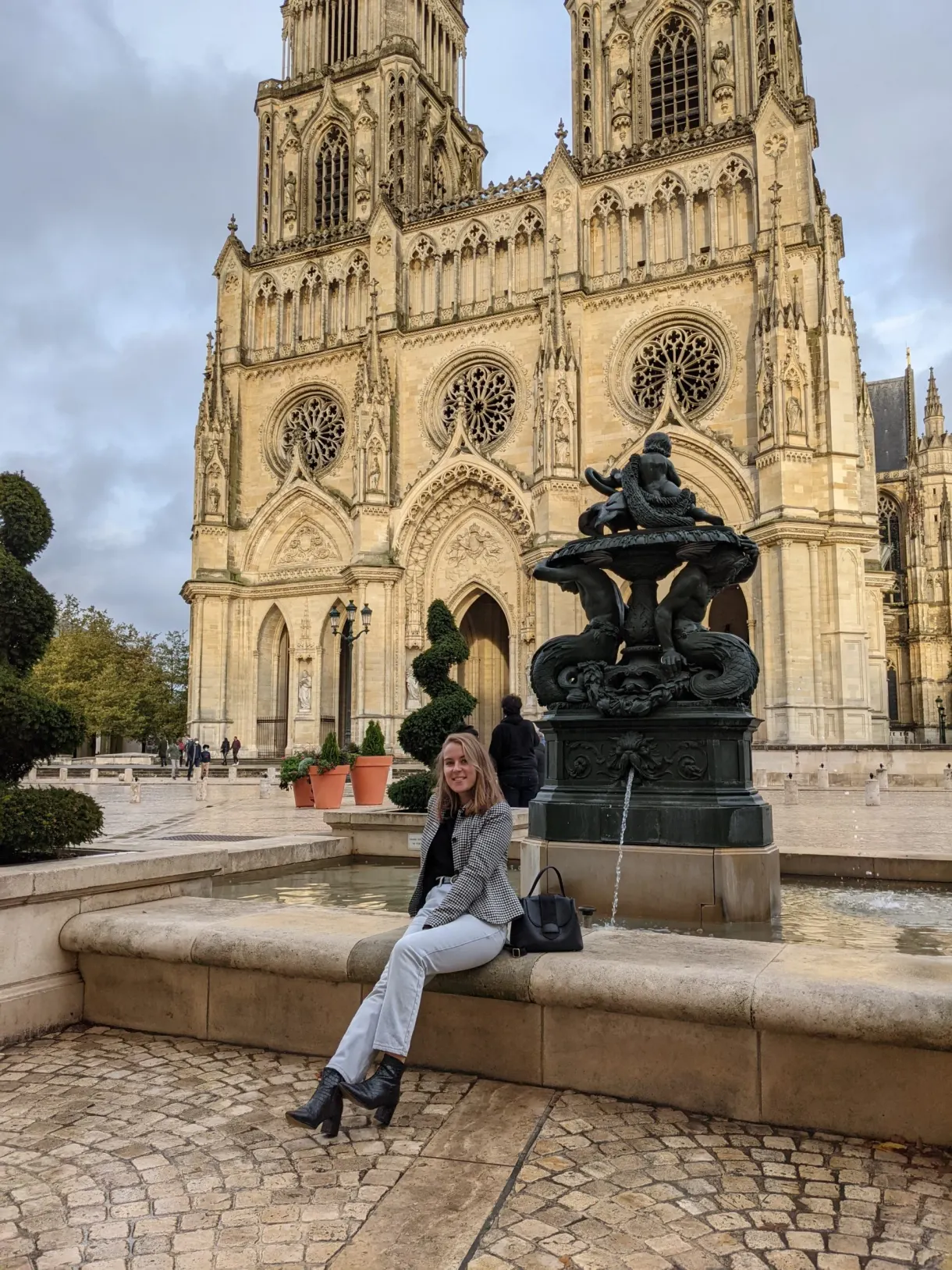 Passer-by sitting on the fountain at the foot of the portal