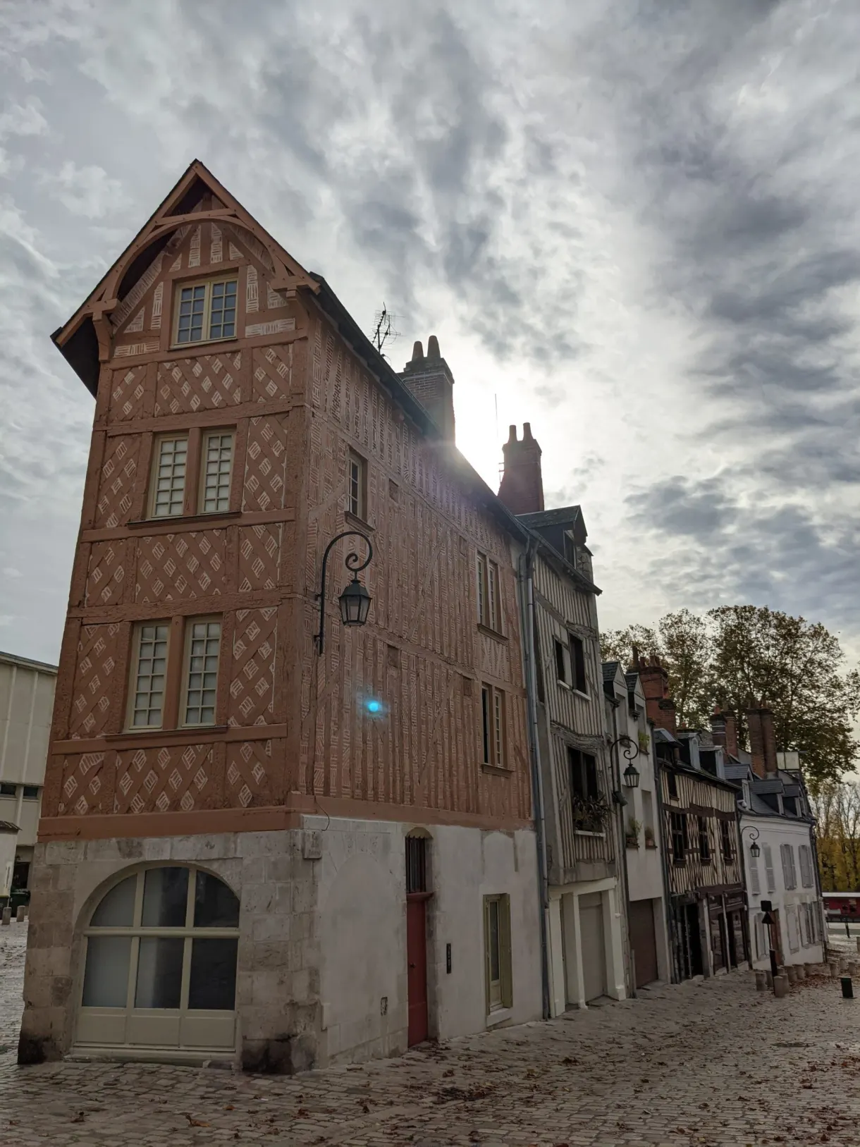 Tall half-timbered house standing alone at the edge of a square