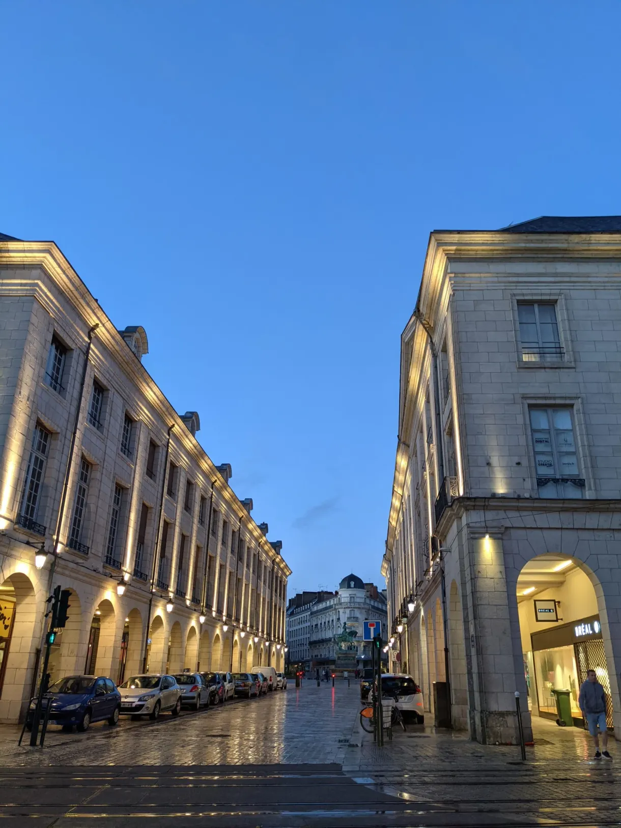 Lit arcades along a wet street in the evening