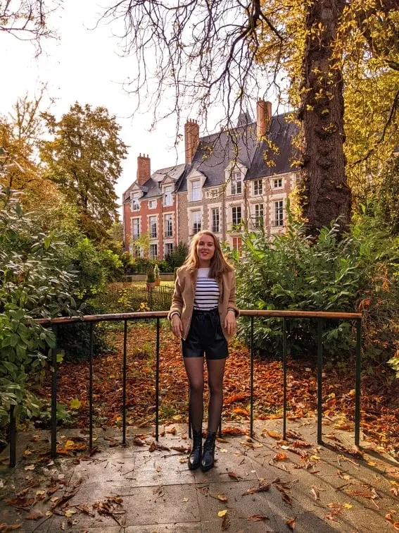 Young woman in front of the garden gate beneath the fallen leaves