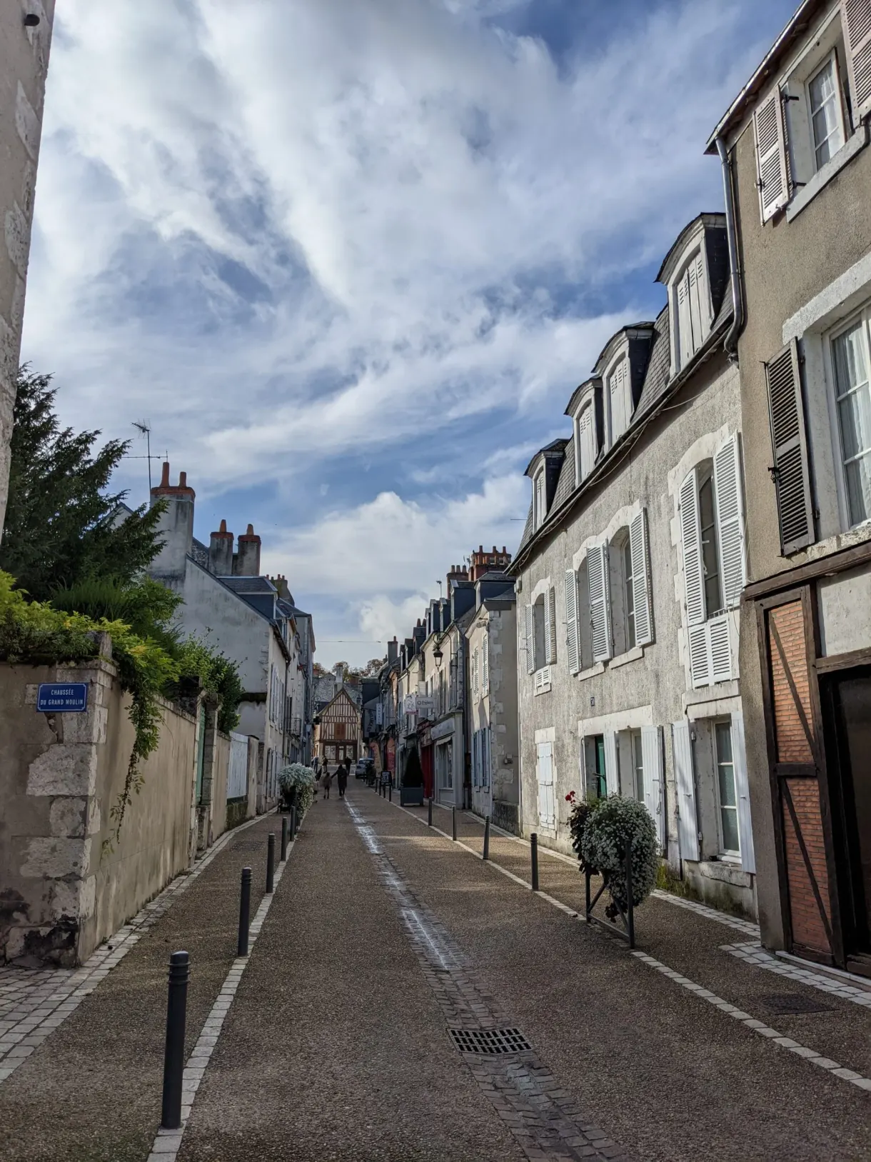 Sloping street lined with pale houses with closed shutters