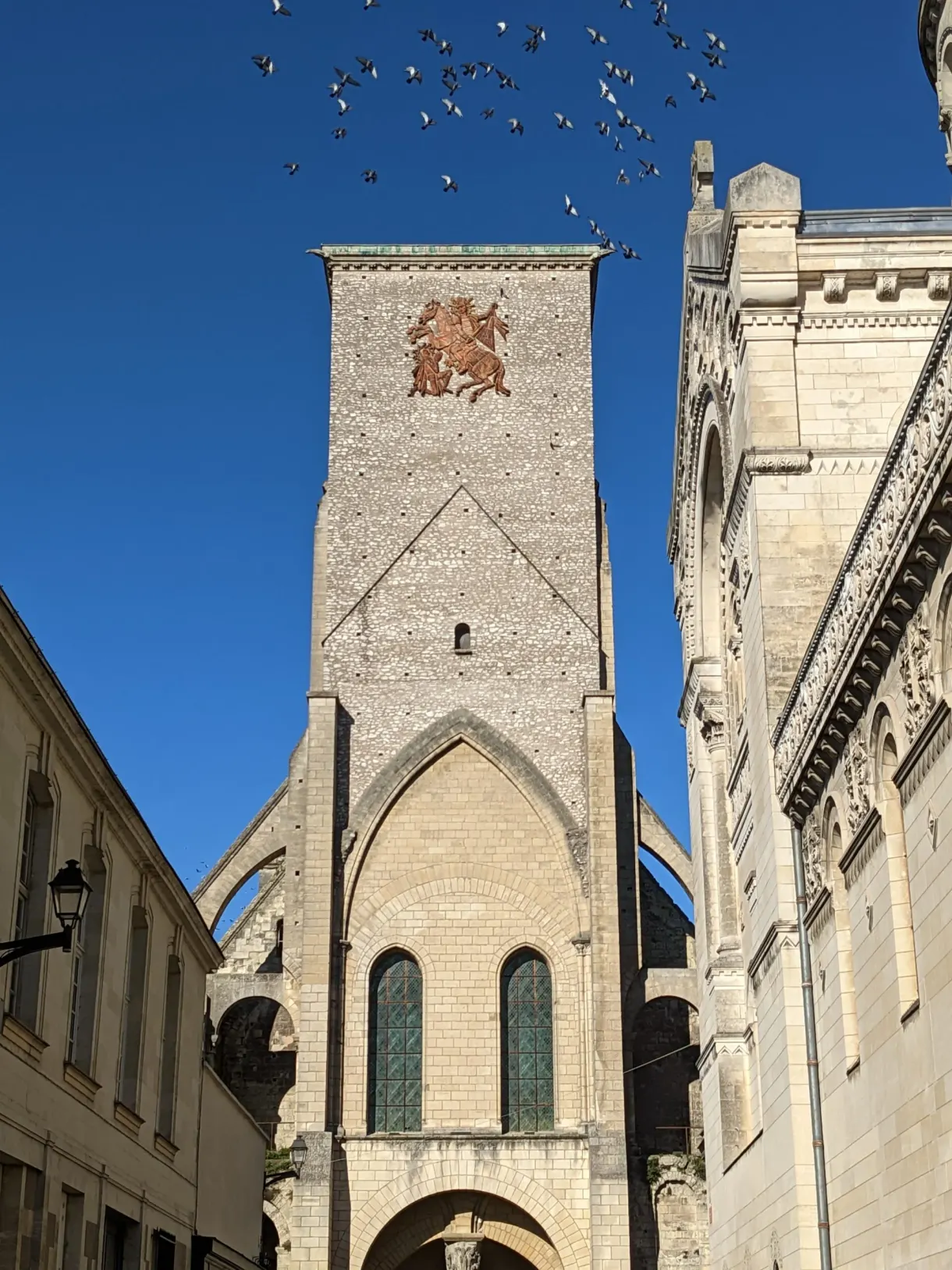 Square stone tower with a flock of birds flying over it