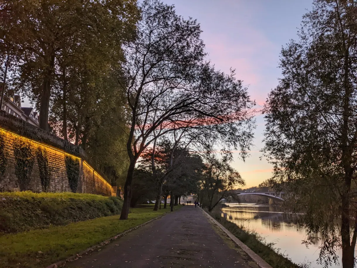 Path running along a green wall under a pink evening sky
