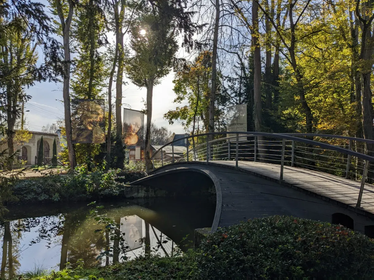 Arched wooden bridge reflected in the pond of the park