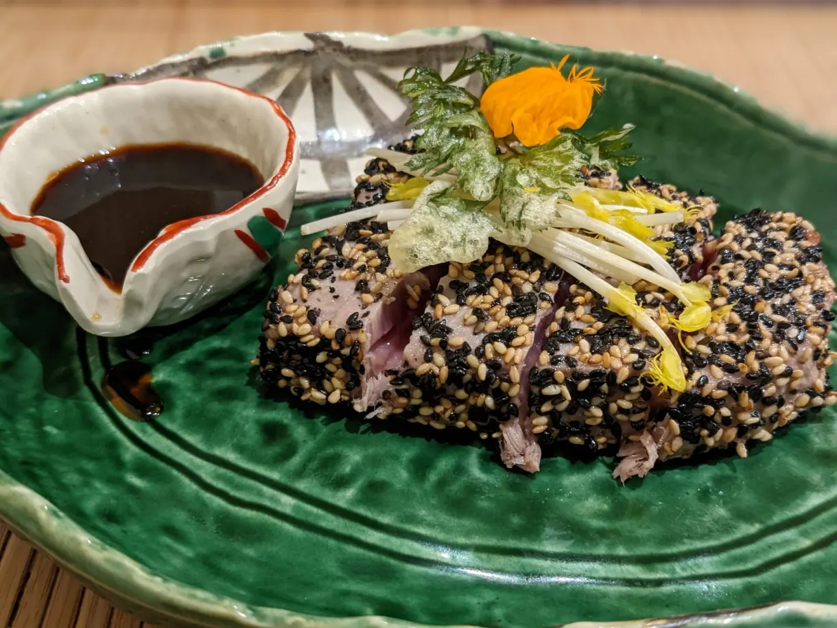 Tuna tataki and black rice on a green plate, soy sauce