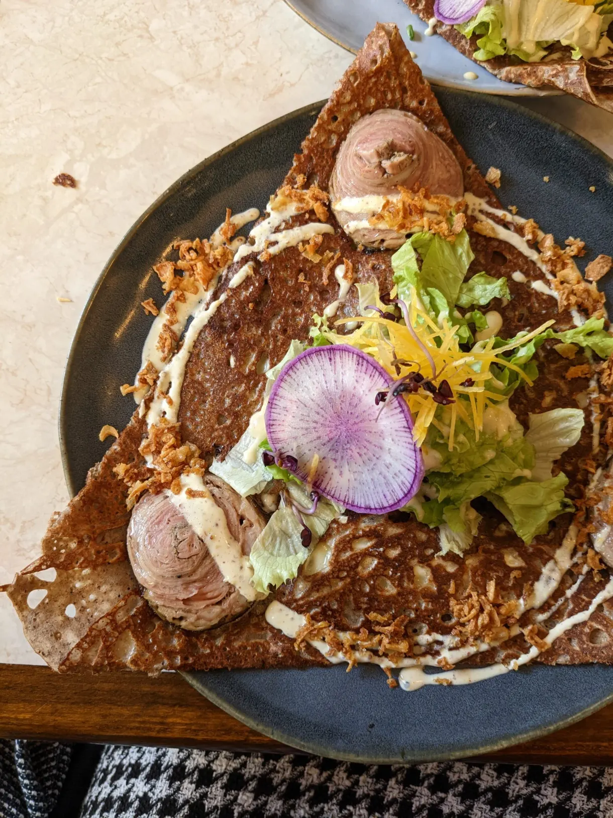 Galette topped with radish, salad and scoops of ice cream