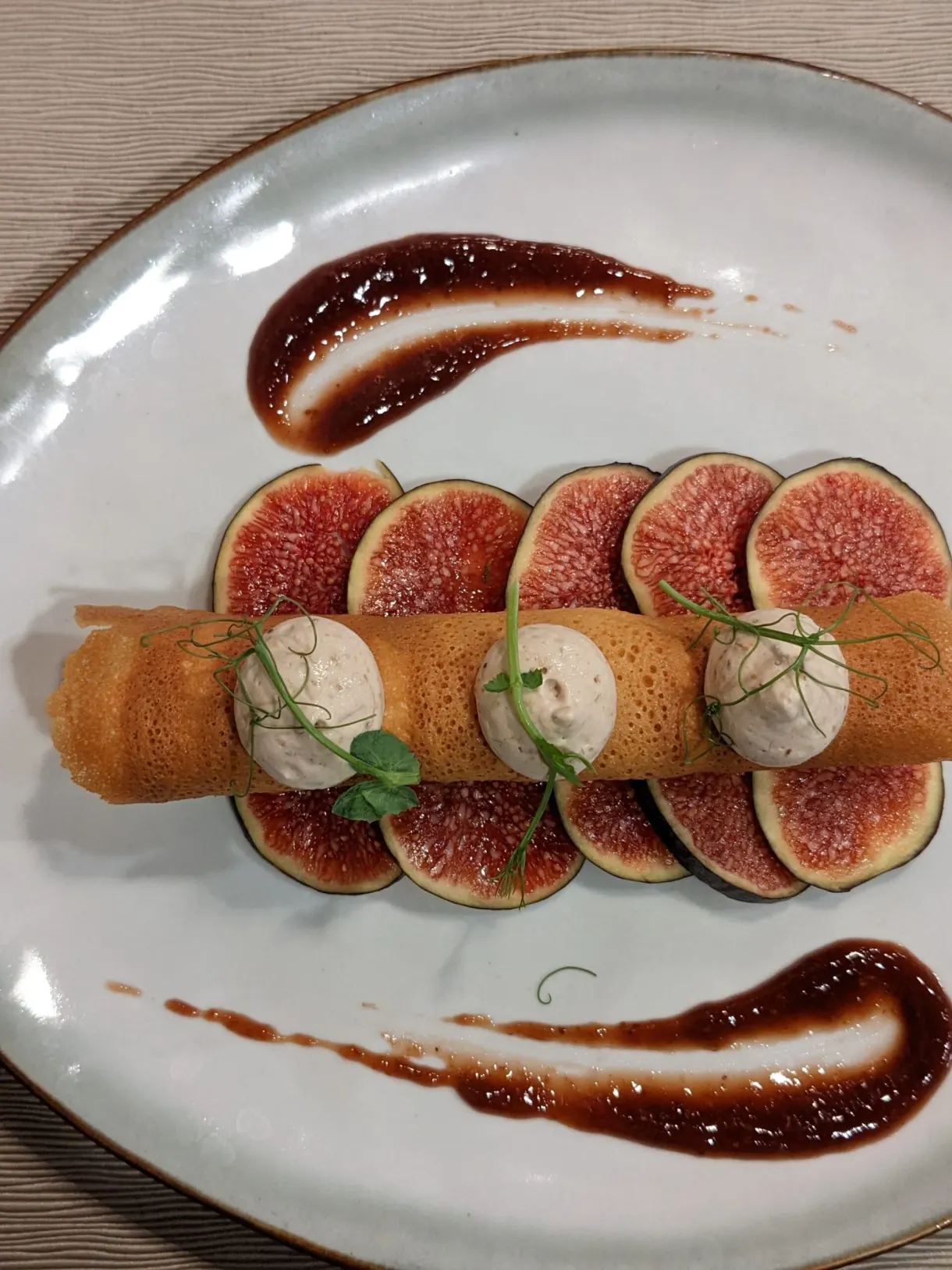 Figs and quenelles lined up between two streaks of sauce