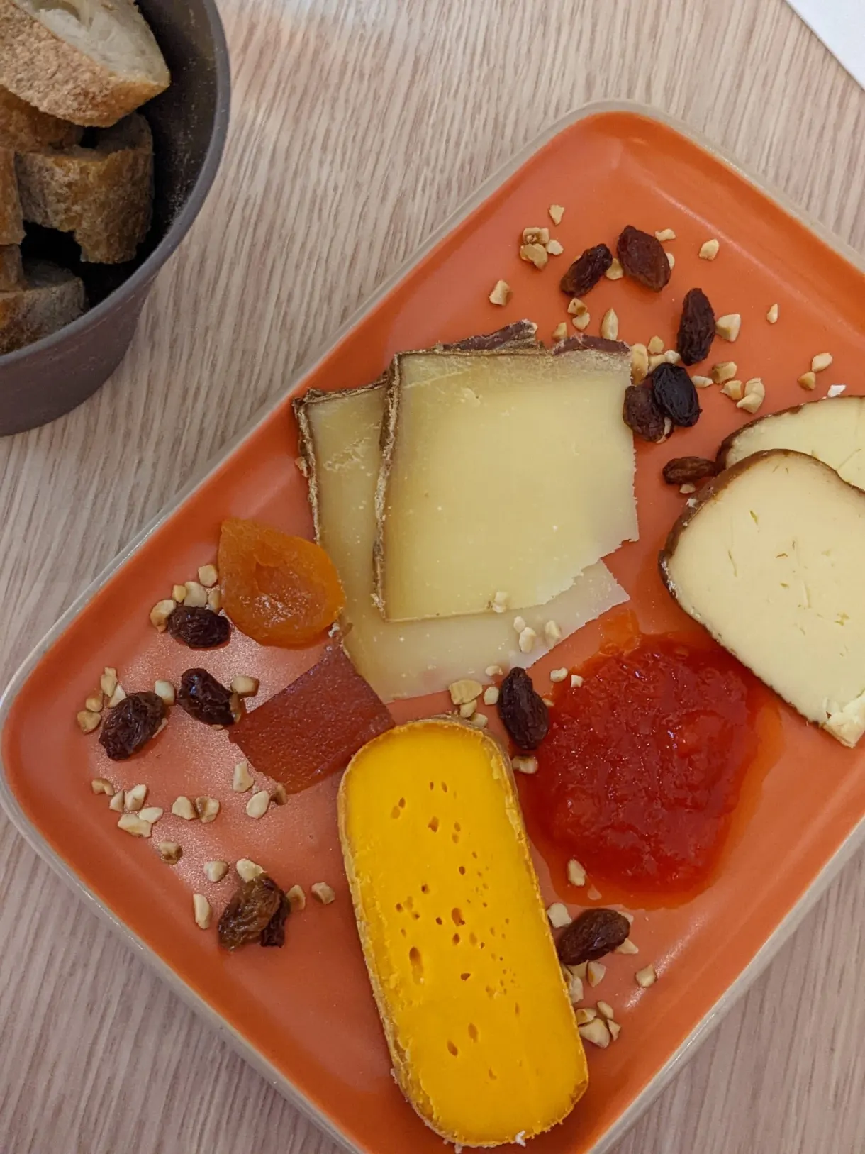 Cheeses, fruit jelly and dried fruit on an orange platter