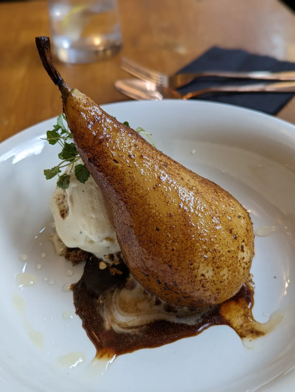 Whole poached pear served with a scoop of ice cream