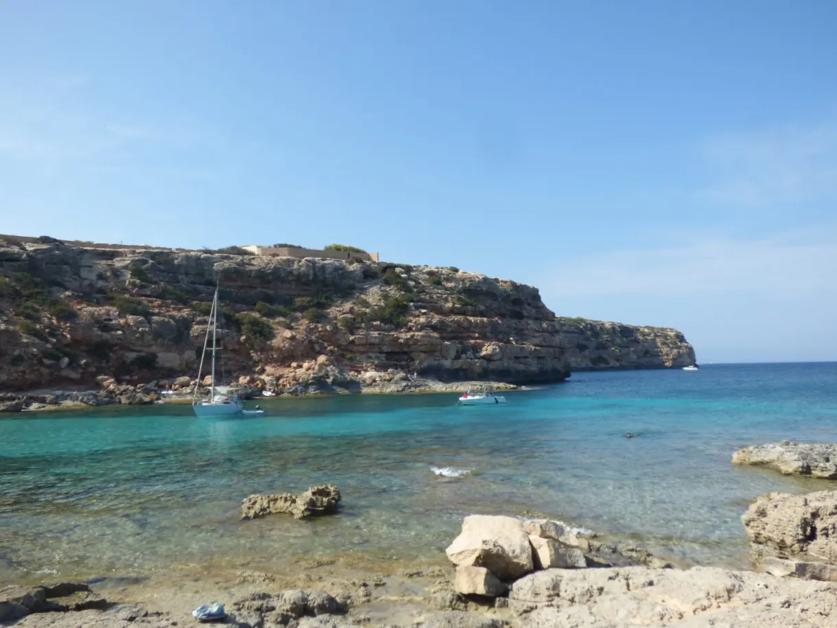 Rocky cove with clear water and sailing boats at anchor